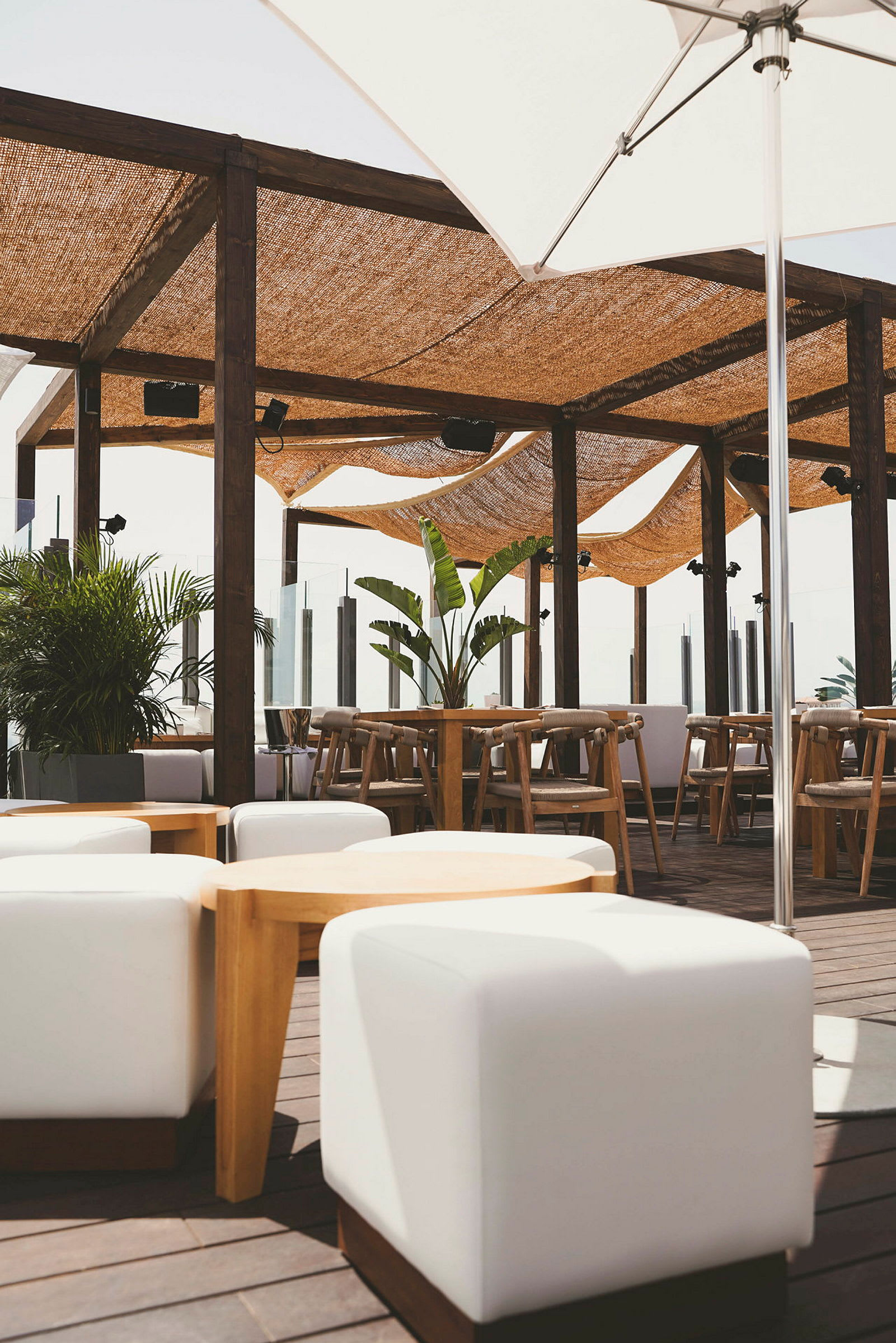 Udendørs terrasse med siddepladser, planter og skyggefulde baldakiner. (AI-genereret tekst)