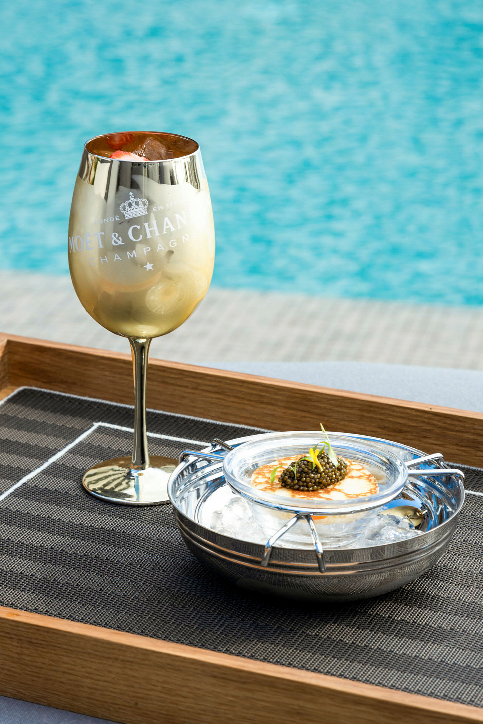 Guldfarvet champagneglas ved siden af en servering med kaviar på is. (AI-genereret tekst)