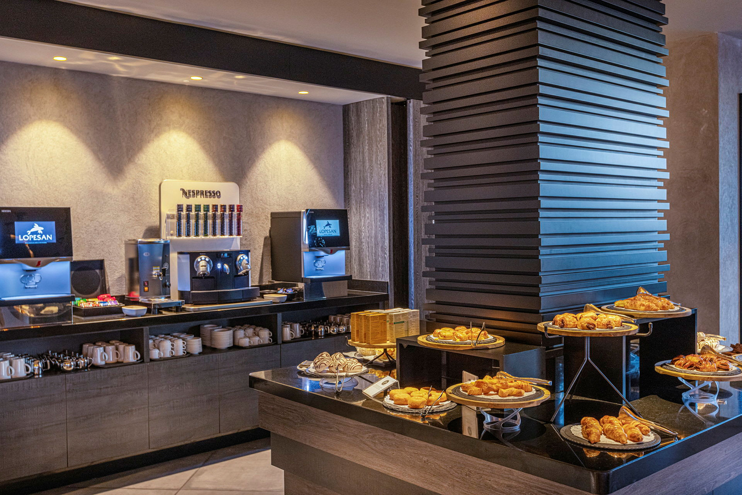Billede af en morgenmadsbuffet med kaffemaskiner og et udvalg af bagværk. (AI-genereret tekst)