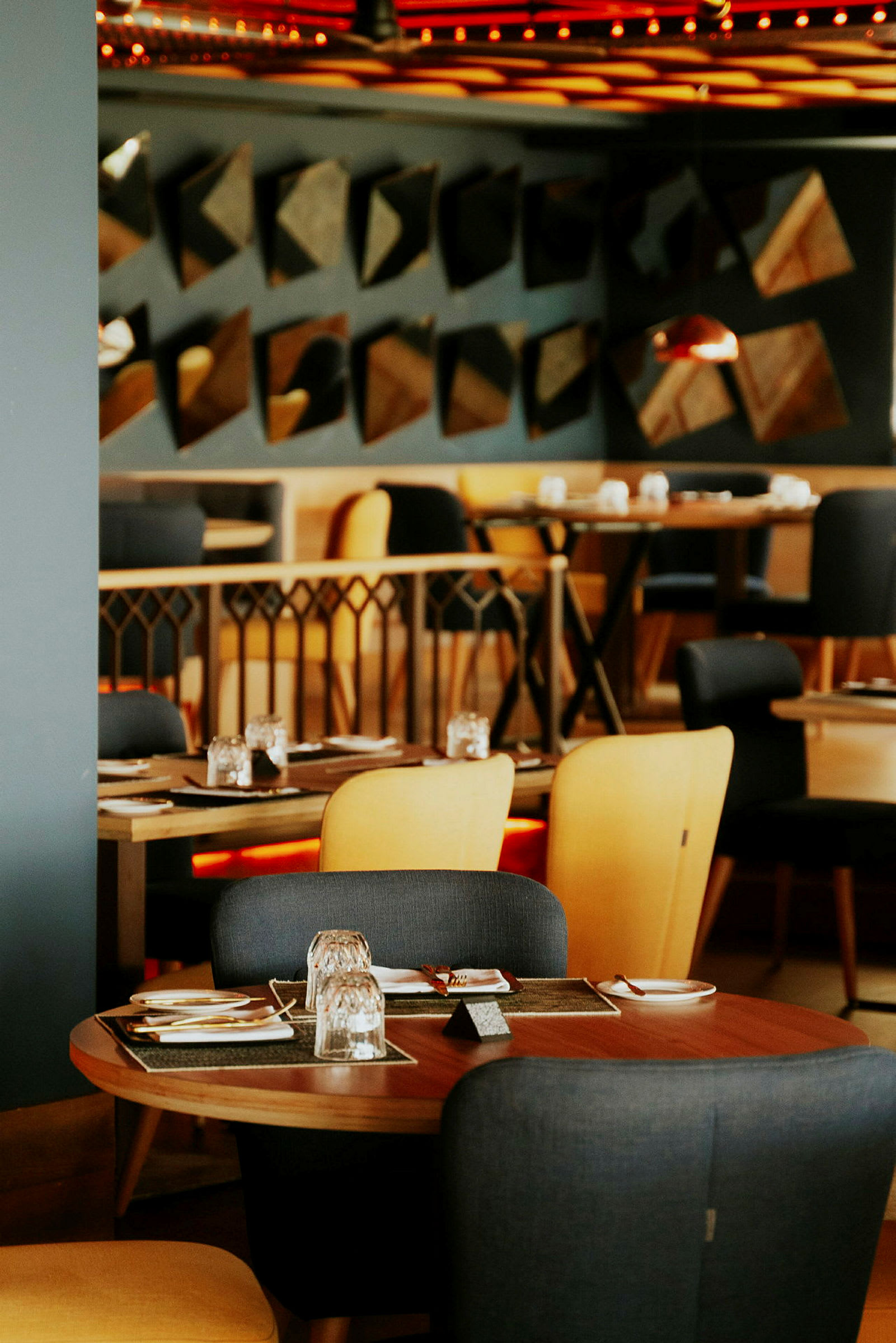 En restaurationsmiljø med borde og stole, dækket til måltider. (AI-genereret tekst)
