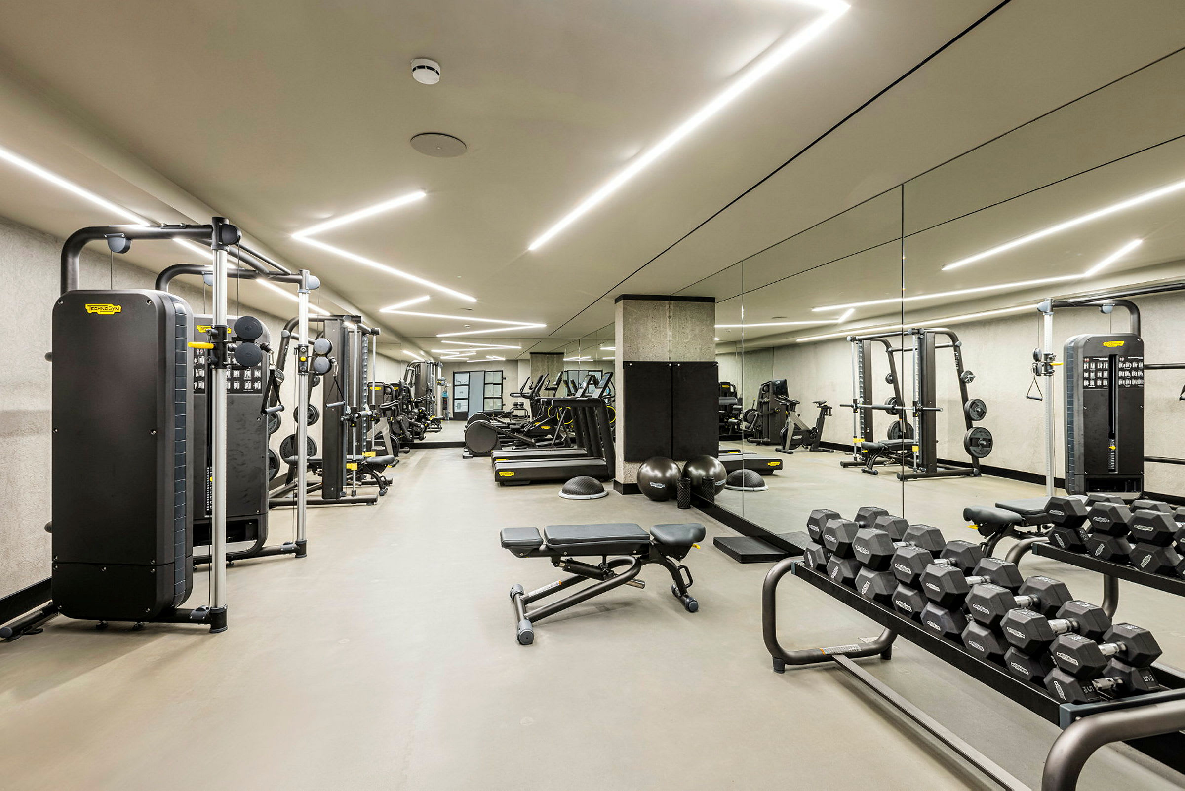 Et fitnesscenter med træningsmaskiner, håndvægte og træningsbænke. (AI-genereret tekst)
