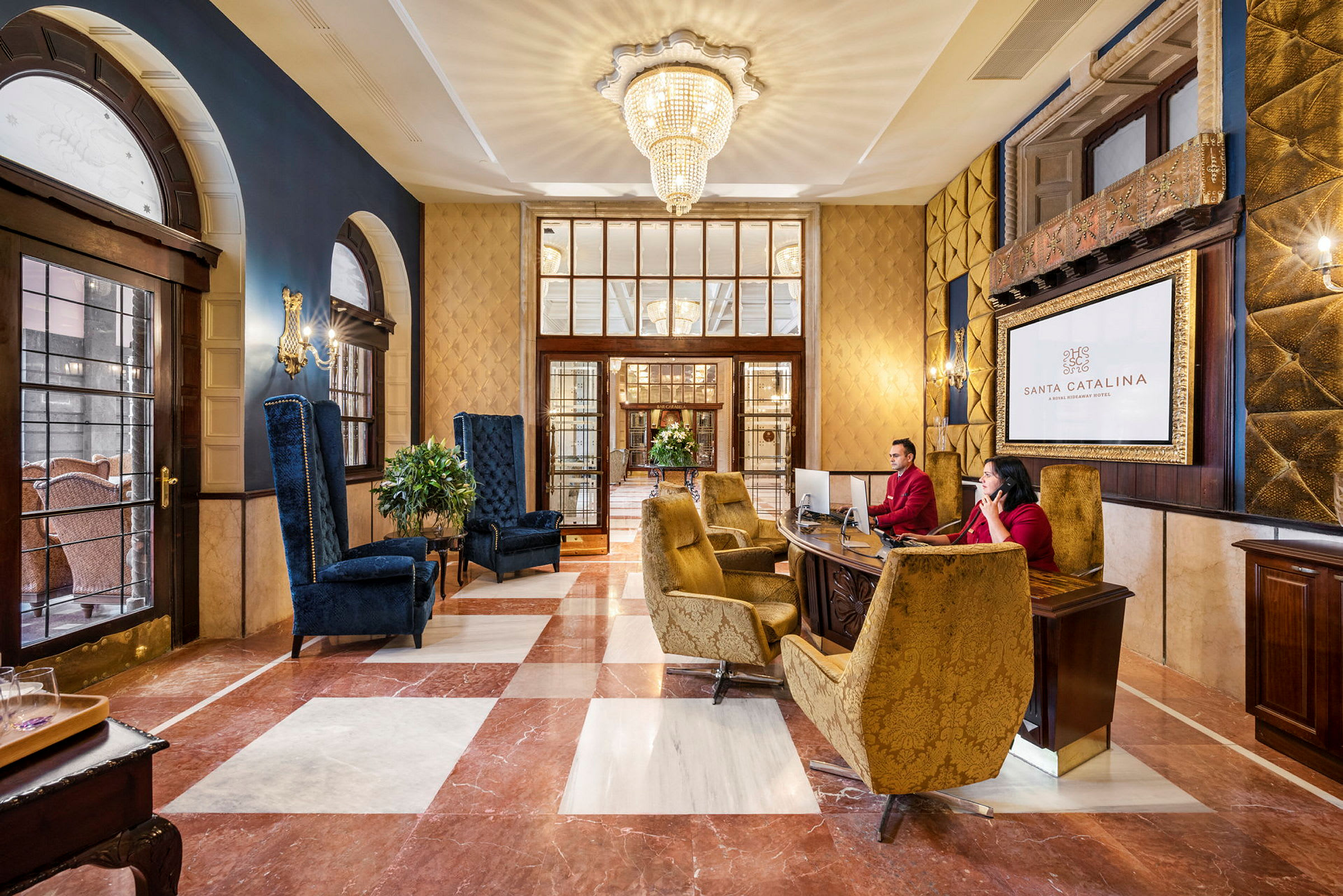 Hotellobby med elegante siddeområder og reception. En stor lysekrone hænger i loftet. (AI-genereret tekst)