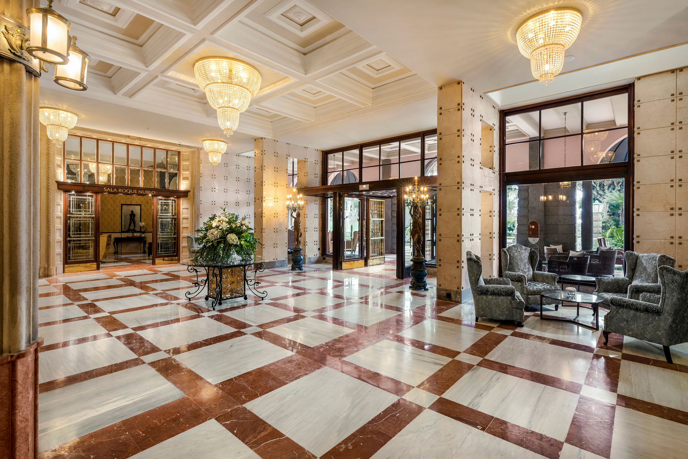 Elegant hotellobby med marmorgulv, store lysekroner og siddeområder. (AI-genereret tekst)