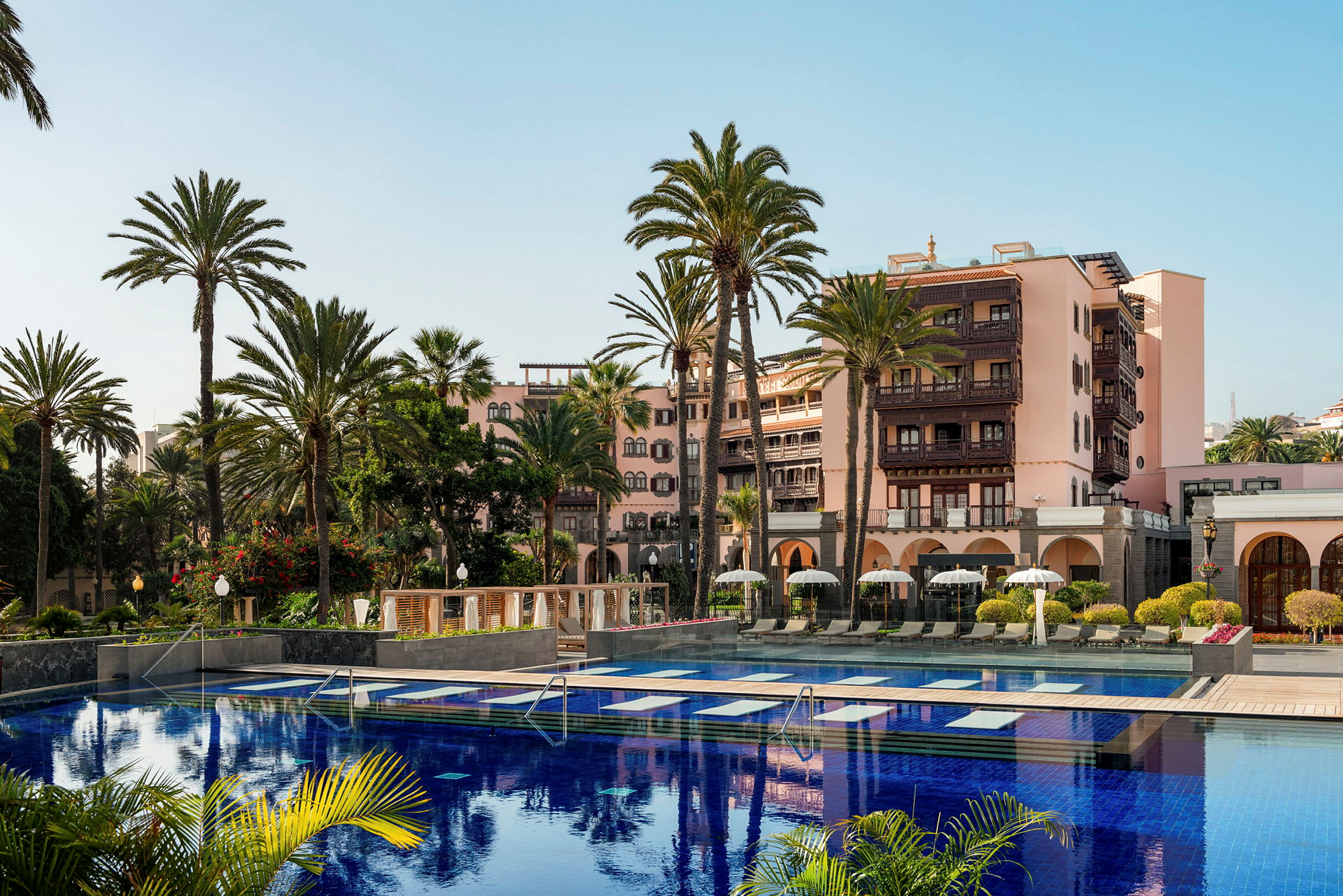 Hotel med pool og palmer i solskinsvejr. (AI-genereret tekst)