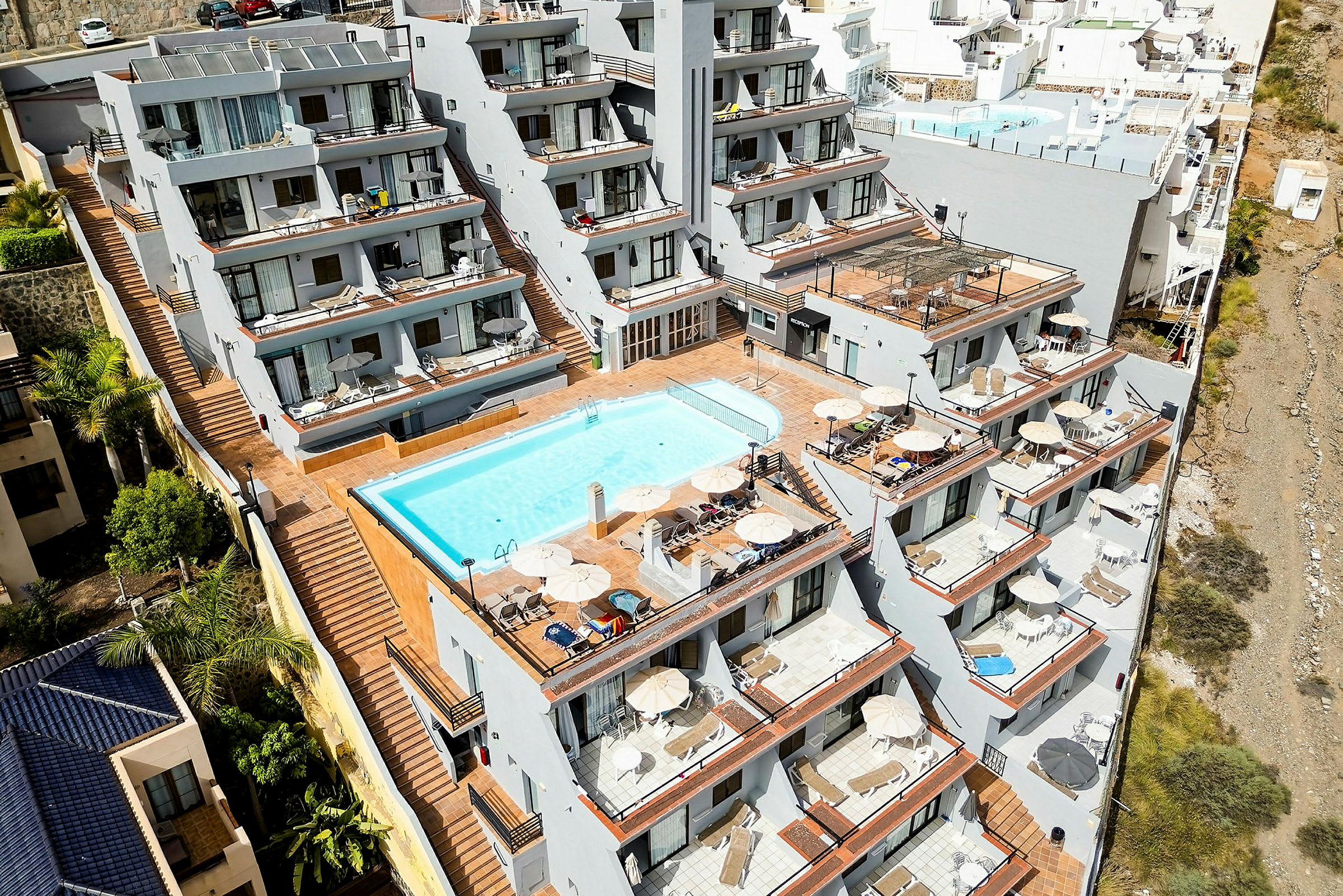 Et hotelkompleks med flere terrasser og en pool. (AI-genereret tekst)