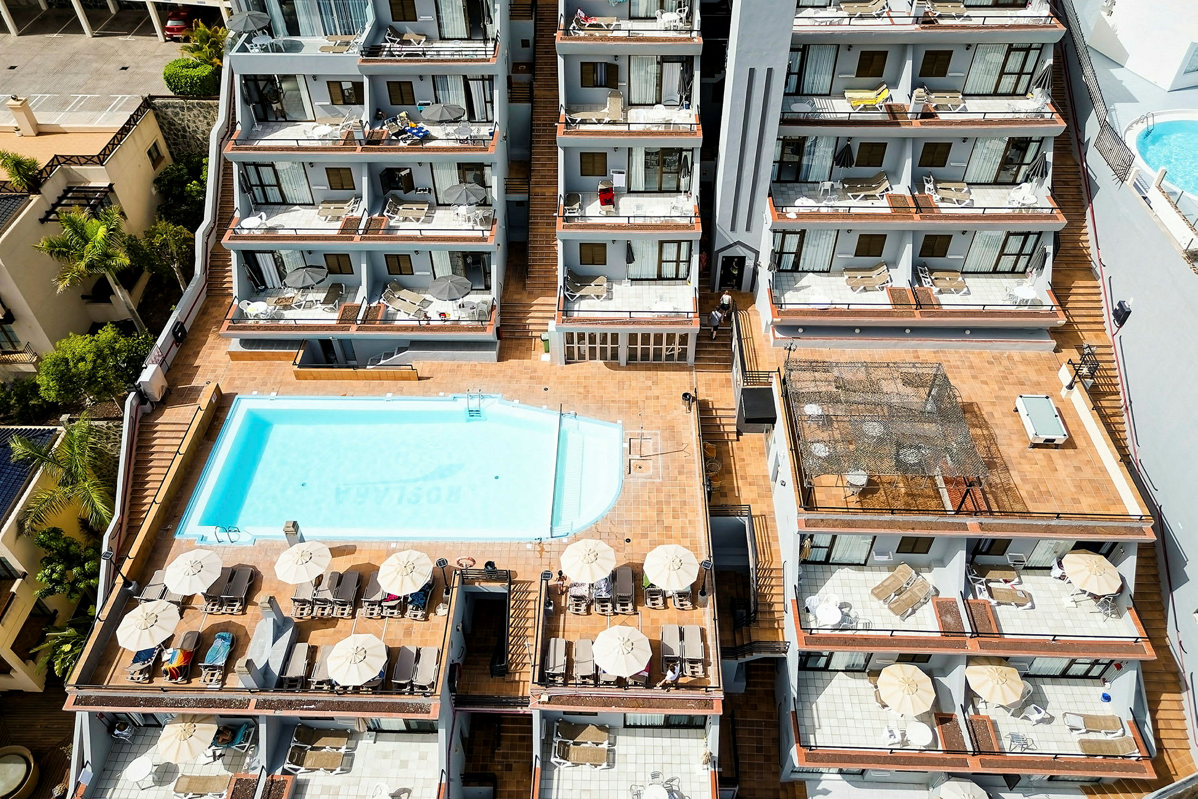 Hotelkompleks med udendørs pool og terrasser. (AI-genereret tekst)