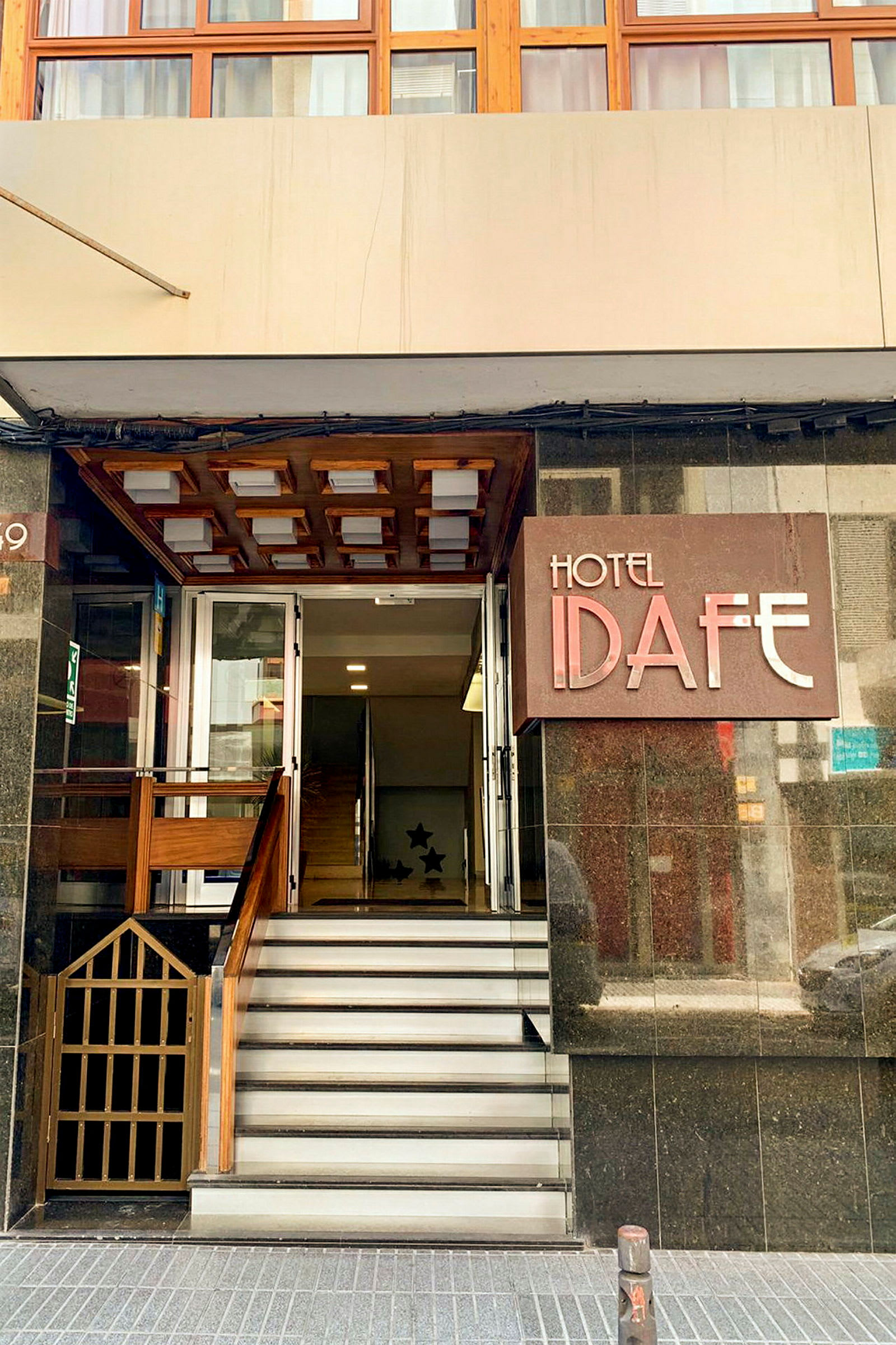 Indgangen til Hotel Idafe med nogle trapper og en dør. (AI-genereret tekst)