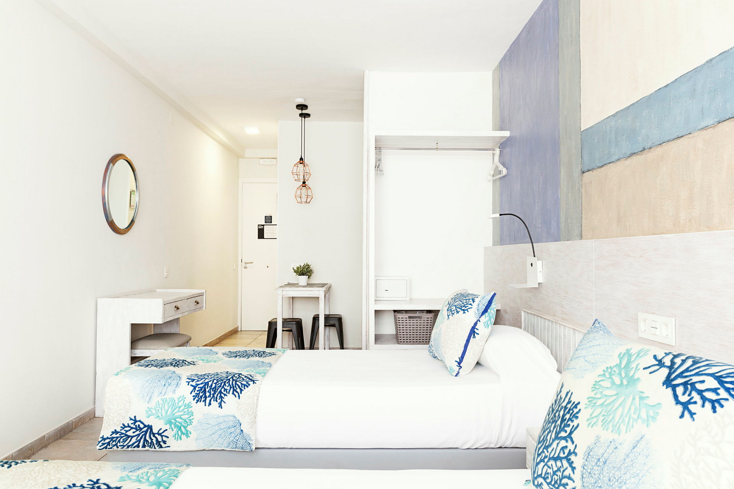 To enkeltsenge med blåmønstrede sengesæt i et lyst og moderne hotelværelse. (AI-genereret tekst)