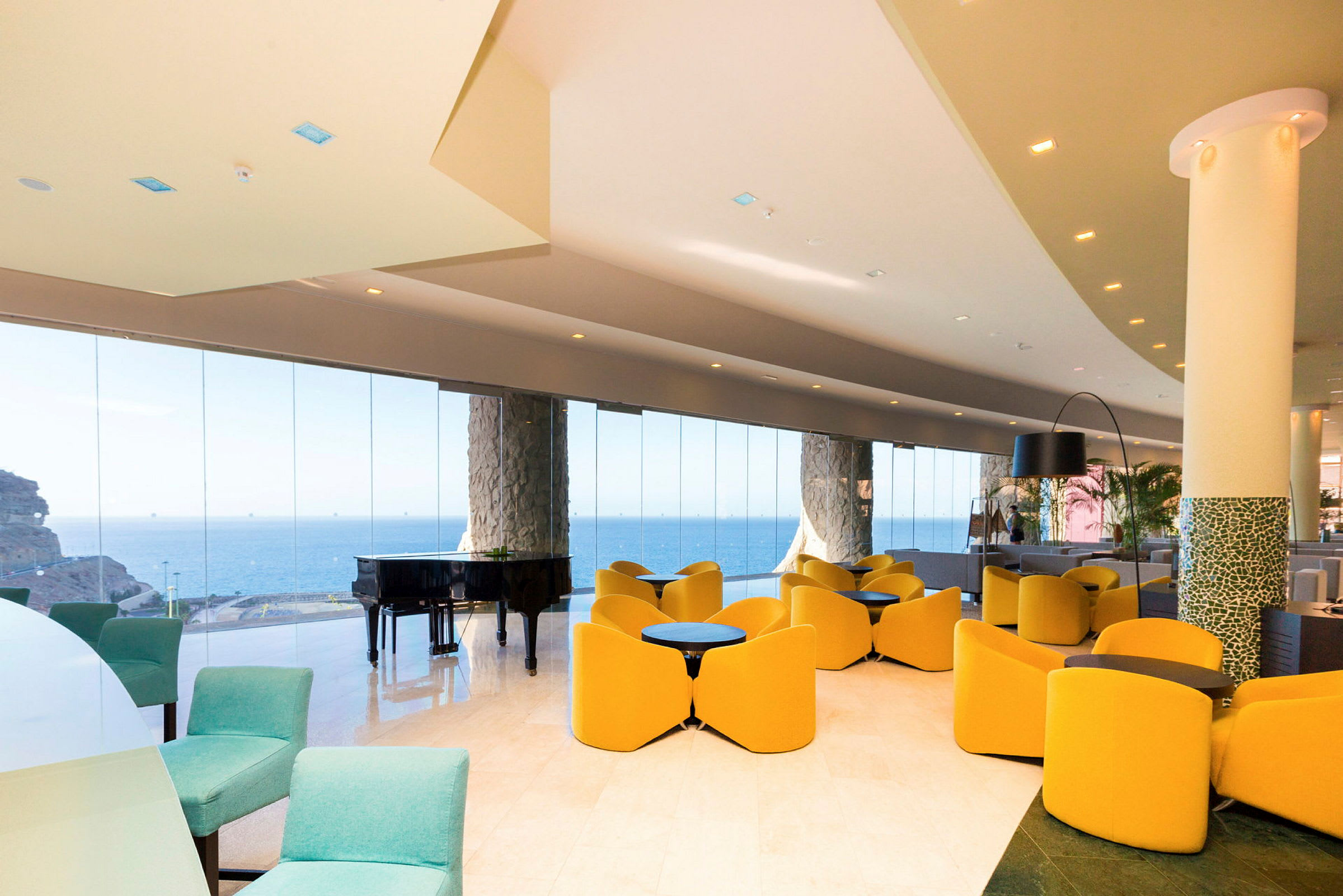 En hotellobby med moderne møbler, store glasvægge og udsigt over havet. (AI-genereret tekst)