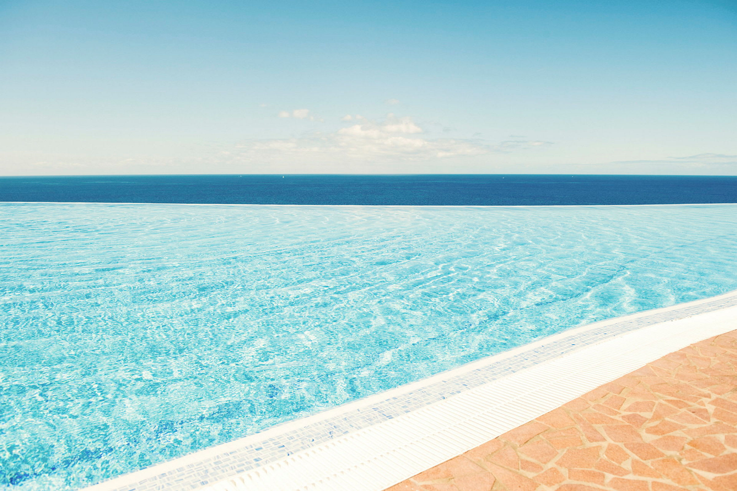 En infinitypool med udsigt over havet under en klar blå himmel. (AI-genereret tekst)