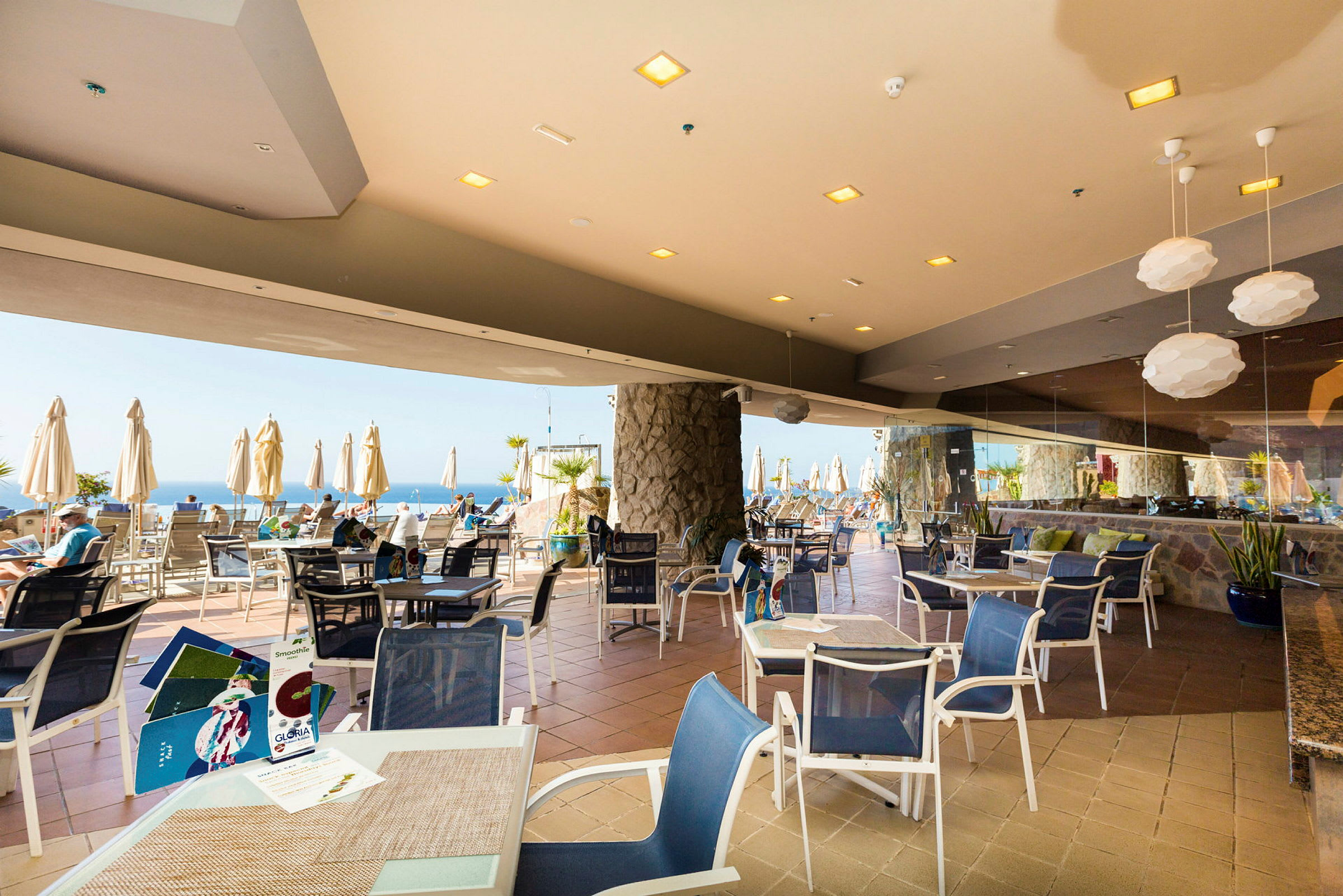 Restaurant taverna med borde og stole samt udsigt mod havet. (AI-genereret tekst)