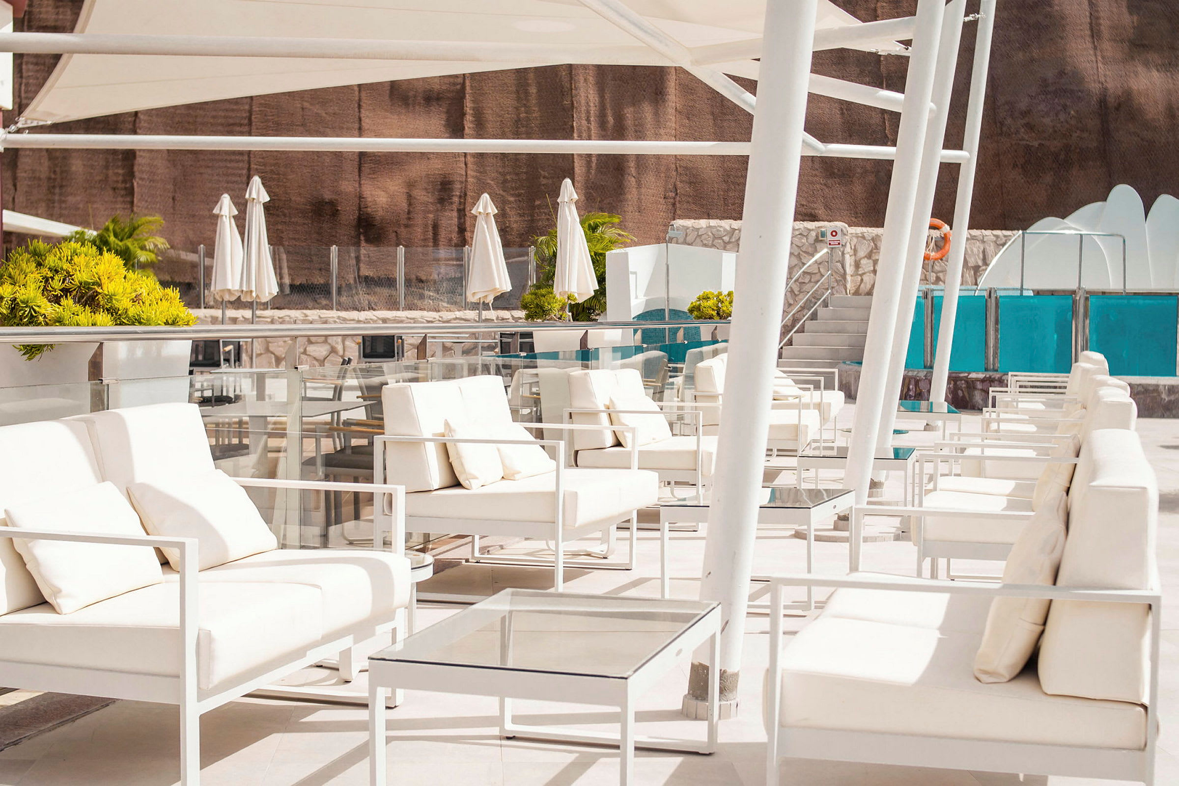 Loungeområde med hvide møbler og parasoller nær en pool. (AI-genereret tekst)