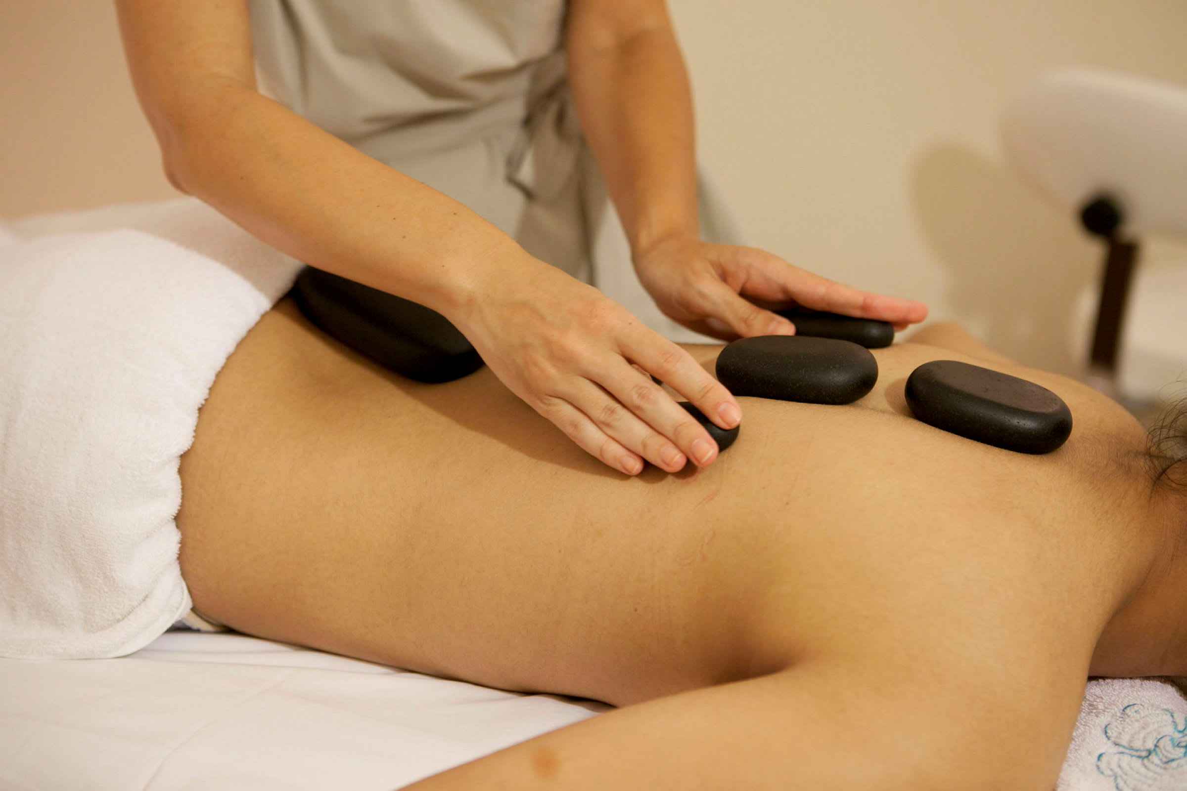 En person får hot stone-massage på ryggen. (AI-genereret tekst)