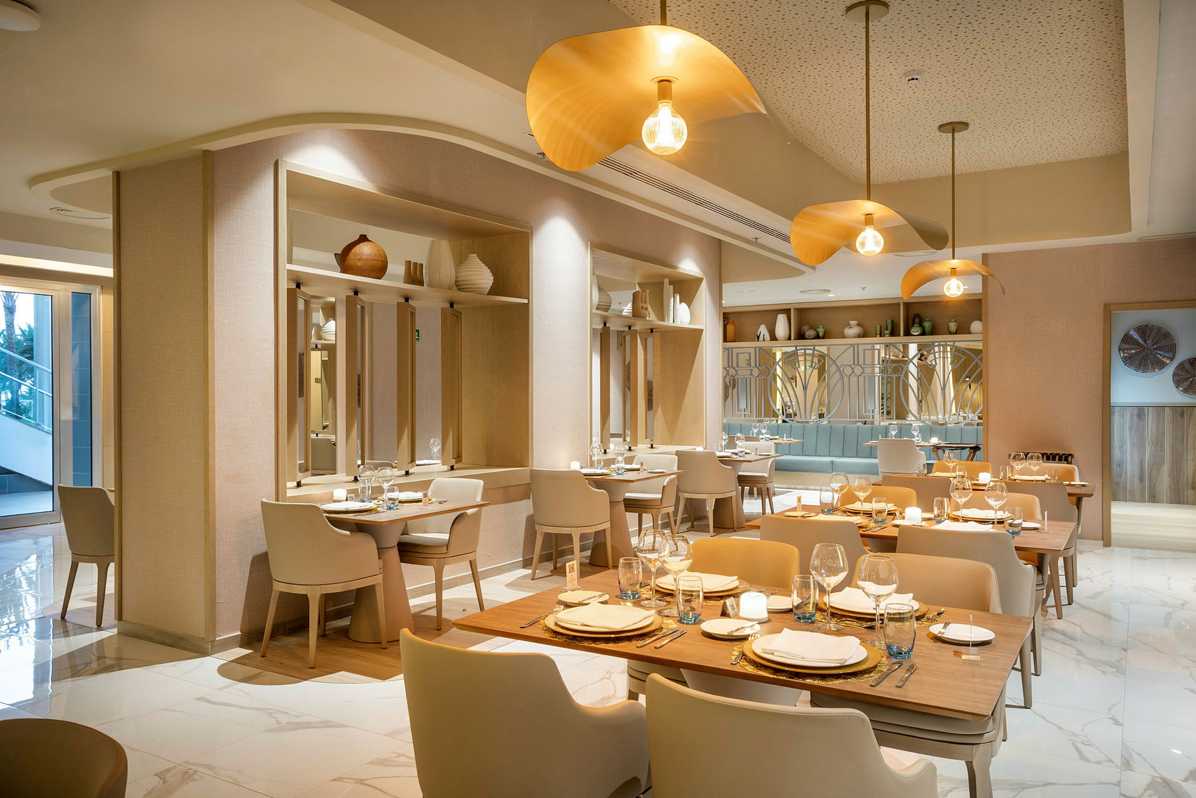 En elegant og moderne restaurant med træborde, lyse stole og gyldne belysningsarmaturer. (AI-genereret tekst)
