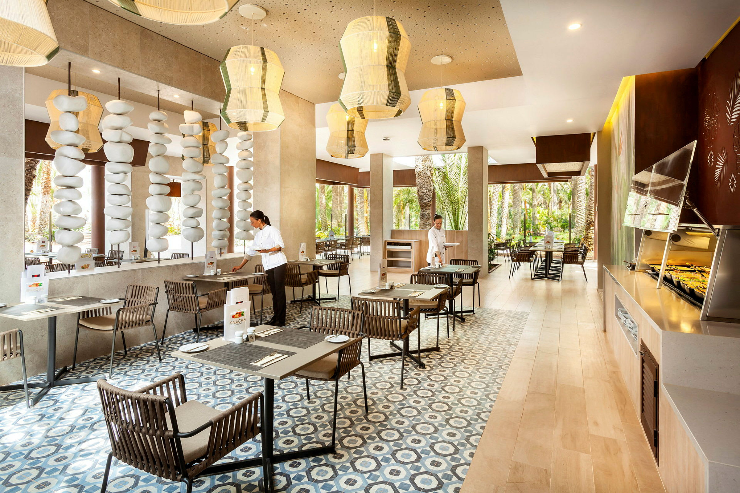 En moderne restaurant med store vinduer, træborde og komfortable stole, samt dekorative loftslamper og stenformationer. (AI-genereret tekst)
