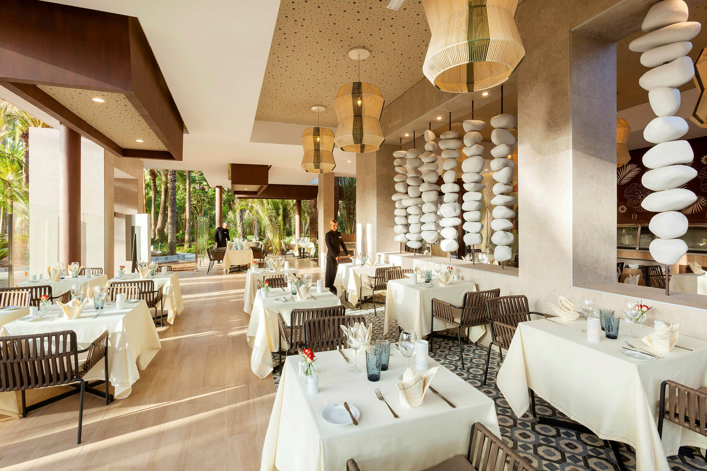 En elegant restaurant med hvide duge, dekorerede borde og store vinduer mod grønt. (AI-genereret tekst)