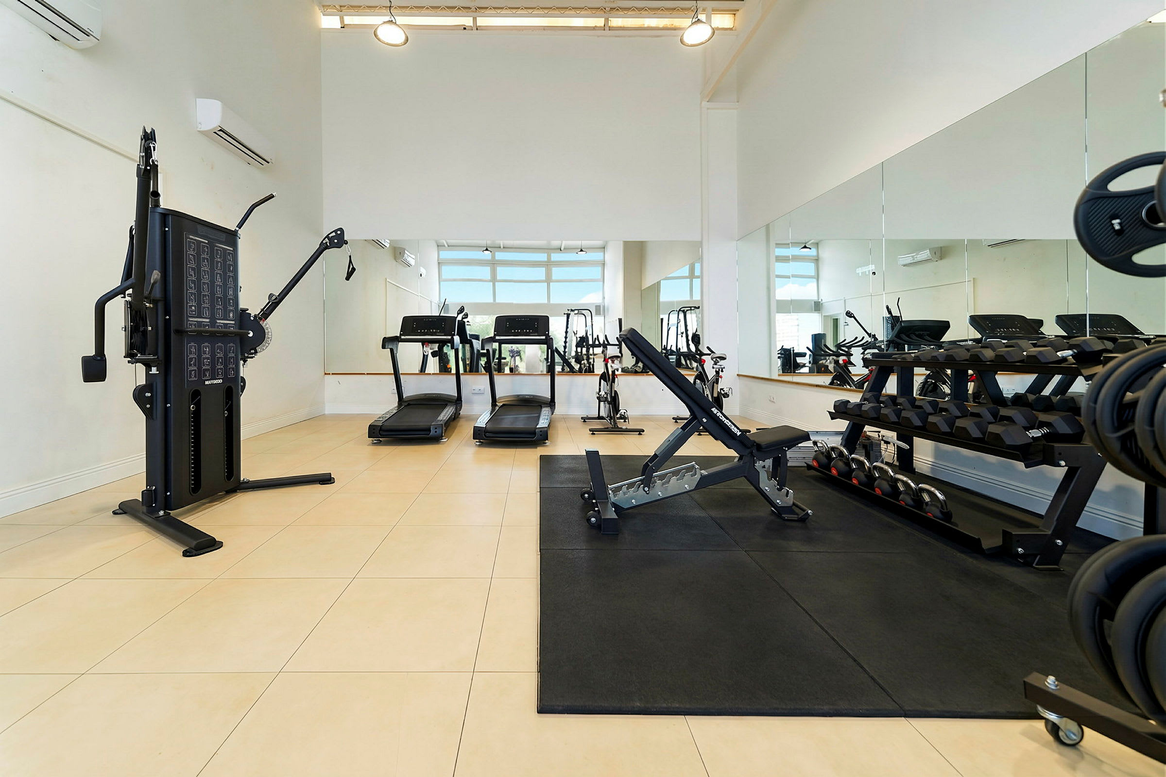 Et fitnesscenter med træningsmaskiner, løbebånd, frie vægte og spejlvægge. (AI-genereret tekst)