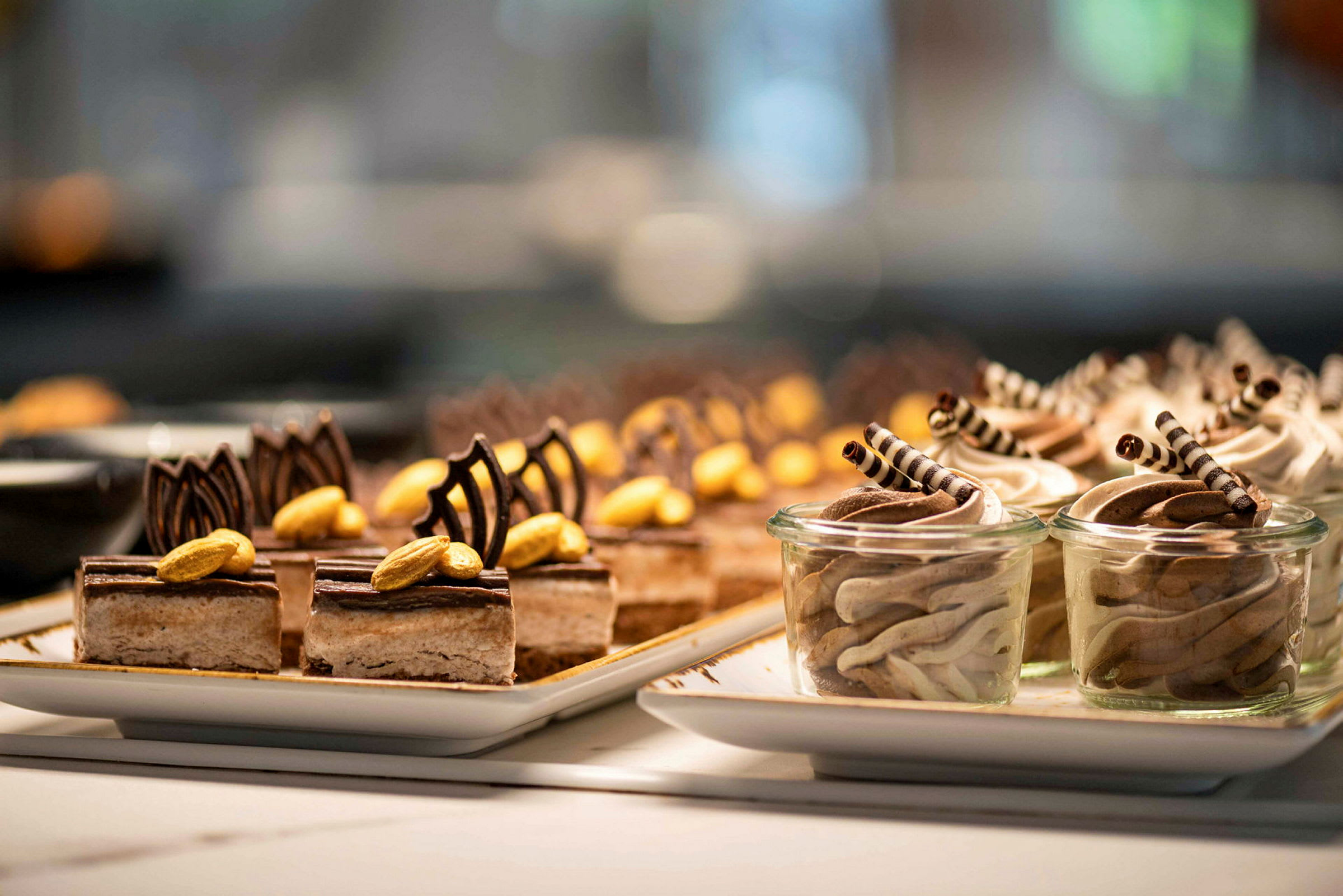 Tallerkener med små desserter pyntet med chokolade og nødder. (AI-genereret tekst)