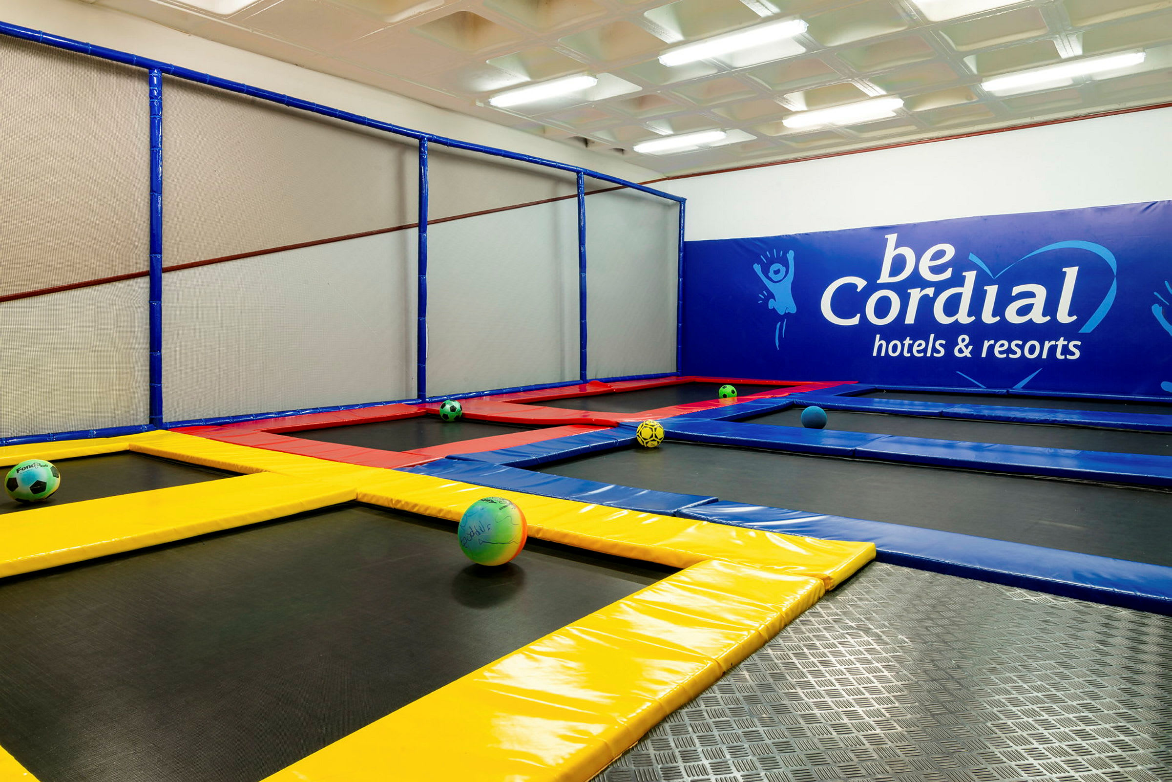 En indendørs trampolinpark med farverige trampoliner og bolde. (AI-genereret tekst)