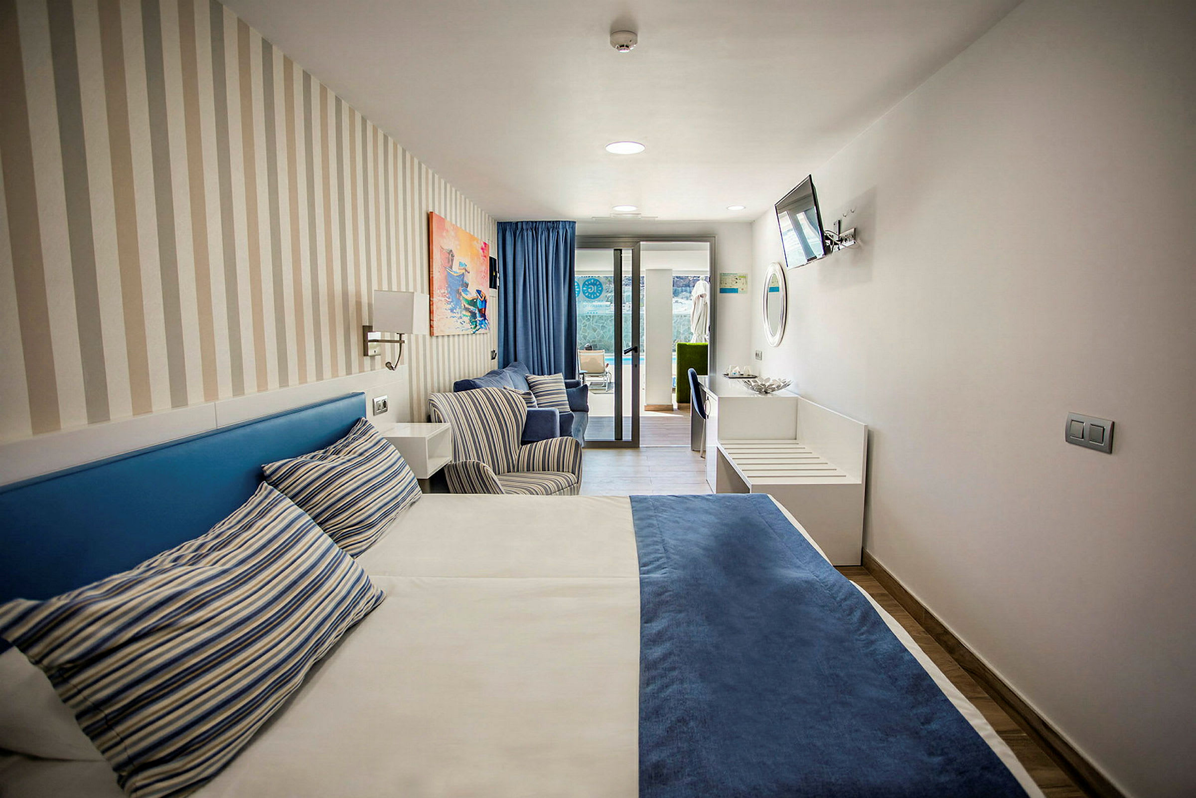 Hotelværelse med en seng, to stole og vindue mod en terrasse. (AI-genereret tekst)