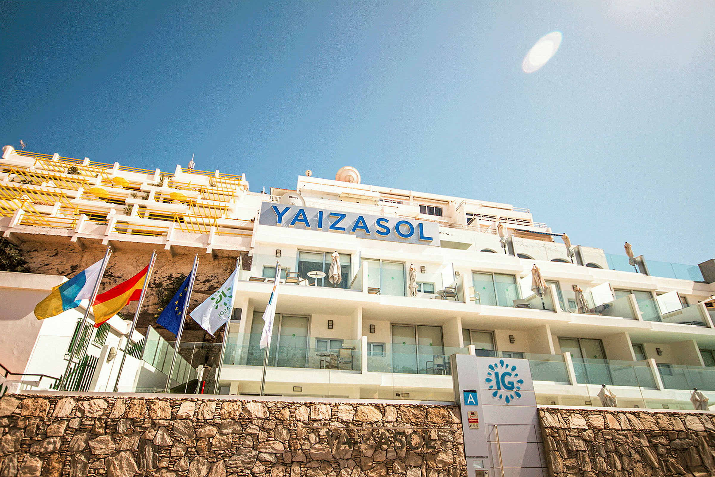 Billede af hotelbygningen Yaizasol med altaner og flag. (AI-genereret tekst)