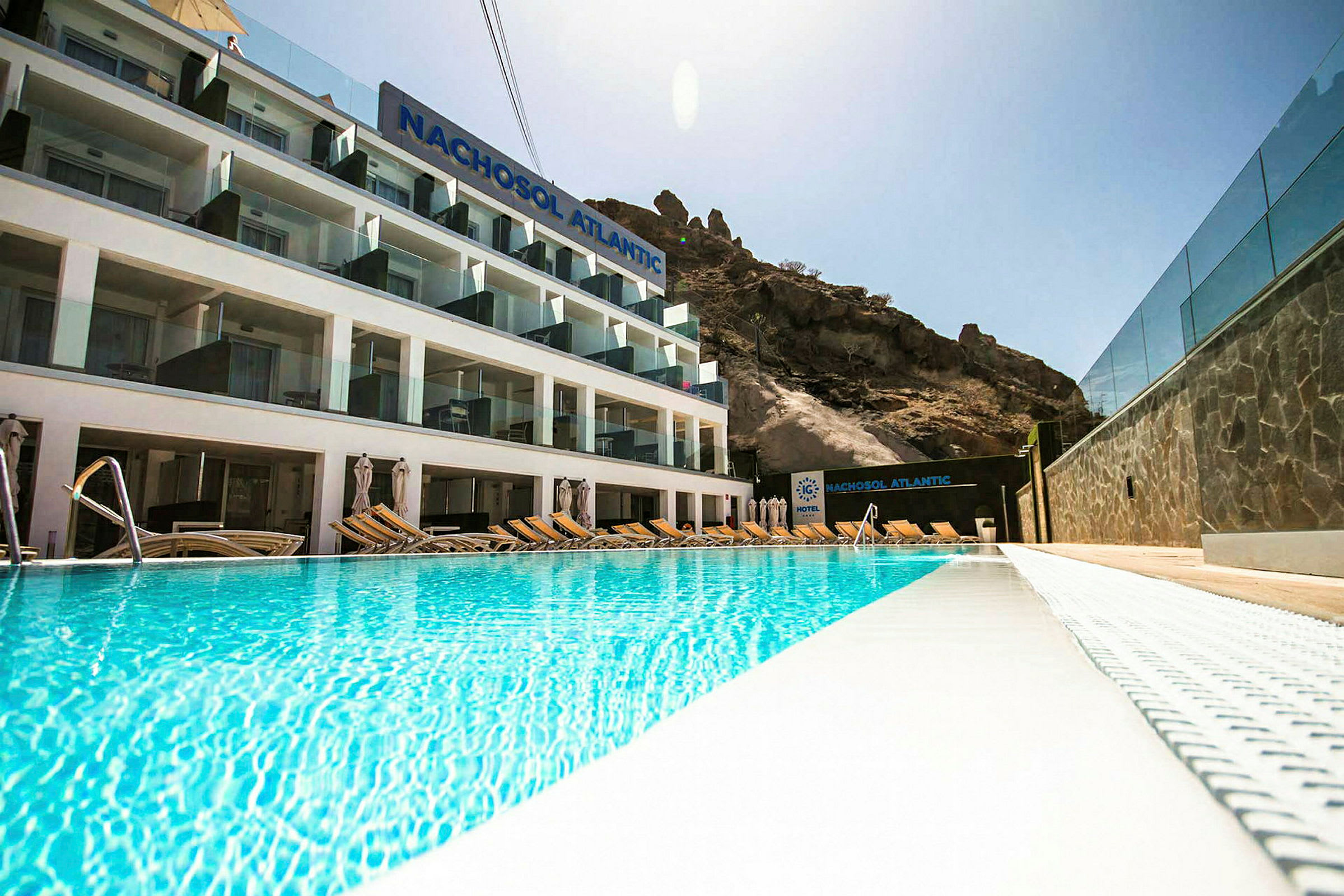 Hotel Nachosol Atlantic med pool foran og bjerge i baggrunden. (AI-genereret tekst)