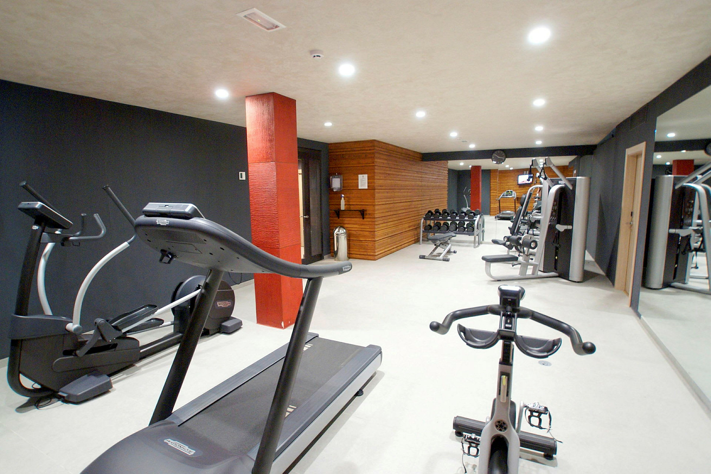 Et fitnesscenter med træningsmaskiner, herunder løbebånd og styrketræningsudstyr. (AI-genereret tekst)