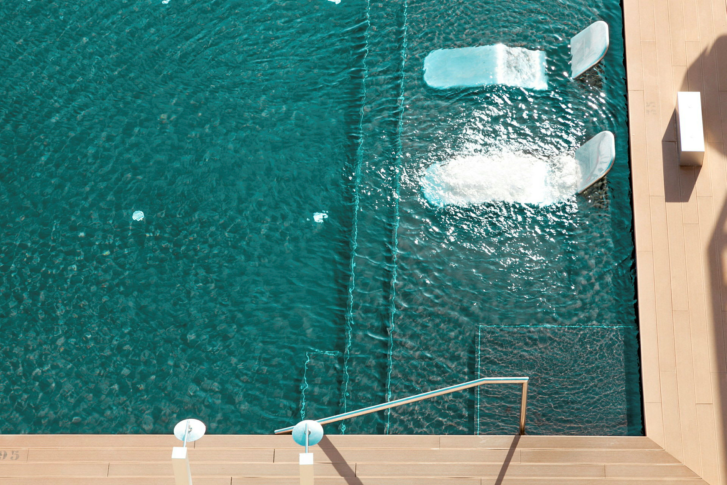 Pool med to indbyggede liggepladser, hvor vand strømmer over. (AI-genereret tekst)