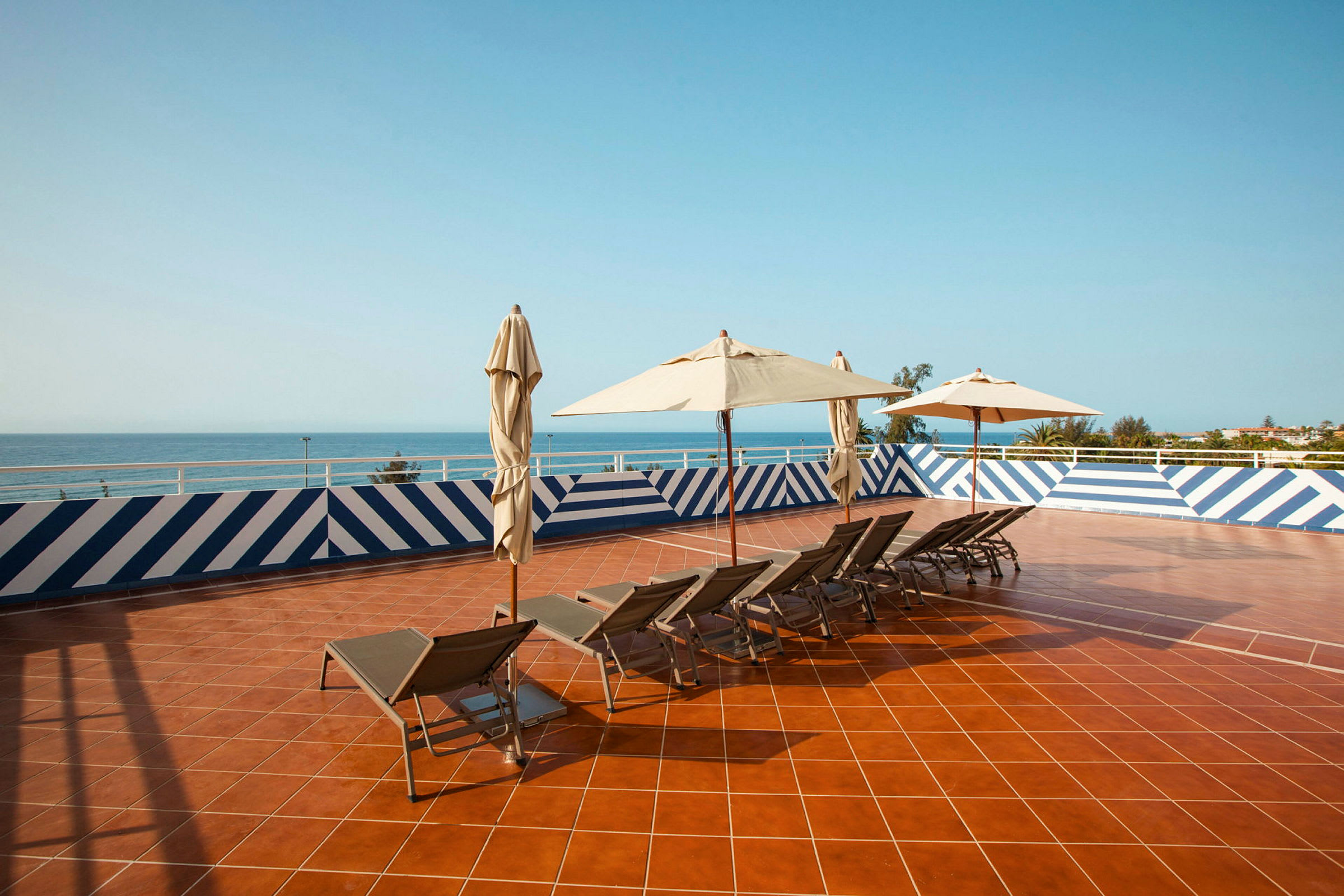 Solterrasse med liggestole og parasoller, udsigt over havet. (AI-genereret tekst)