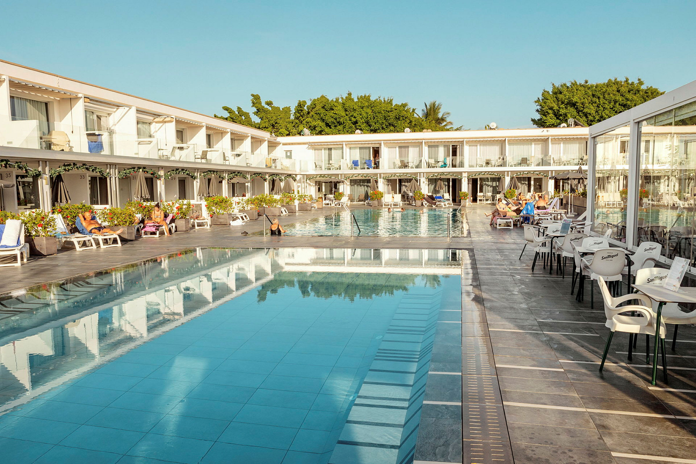 Hotelområde med pool, liggestole og siddepladser. (AI-genereret tekst)