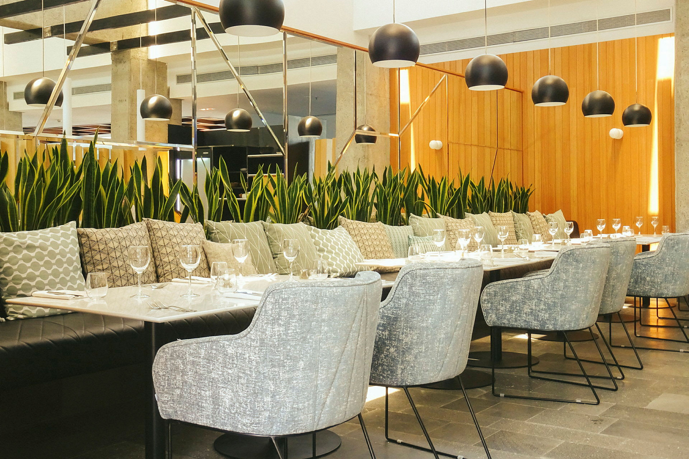 Moderne restaurantindretning med et langbord omgivet af stole og planteudsmykning. (AI-genereret tekst)