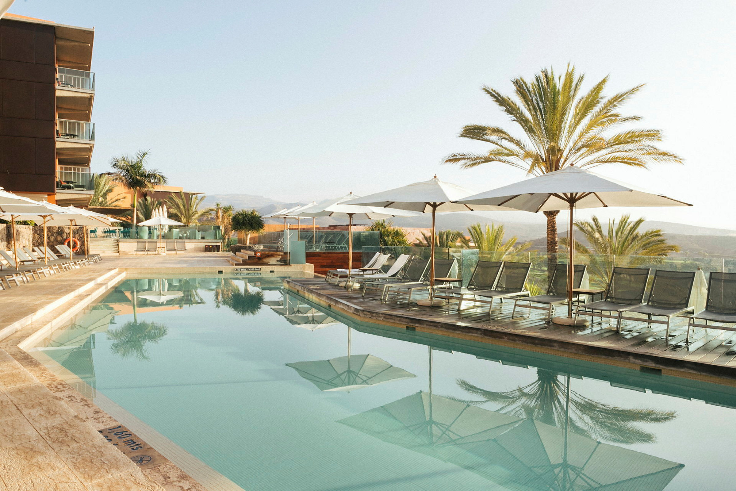 Udendørs pool ved hotel med liggestole og parasoller. (AI-genereret tekst)