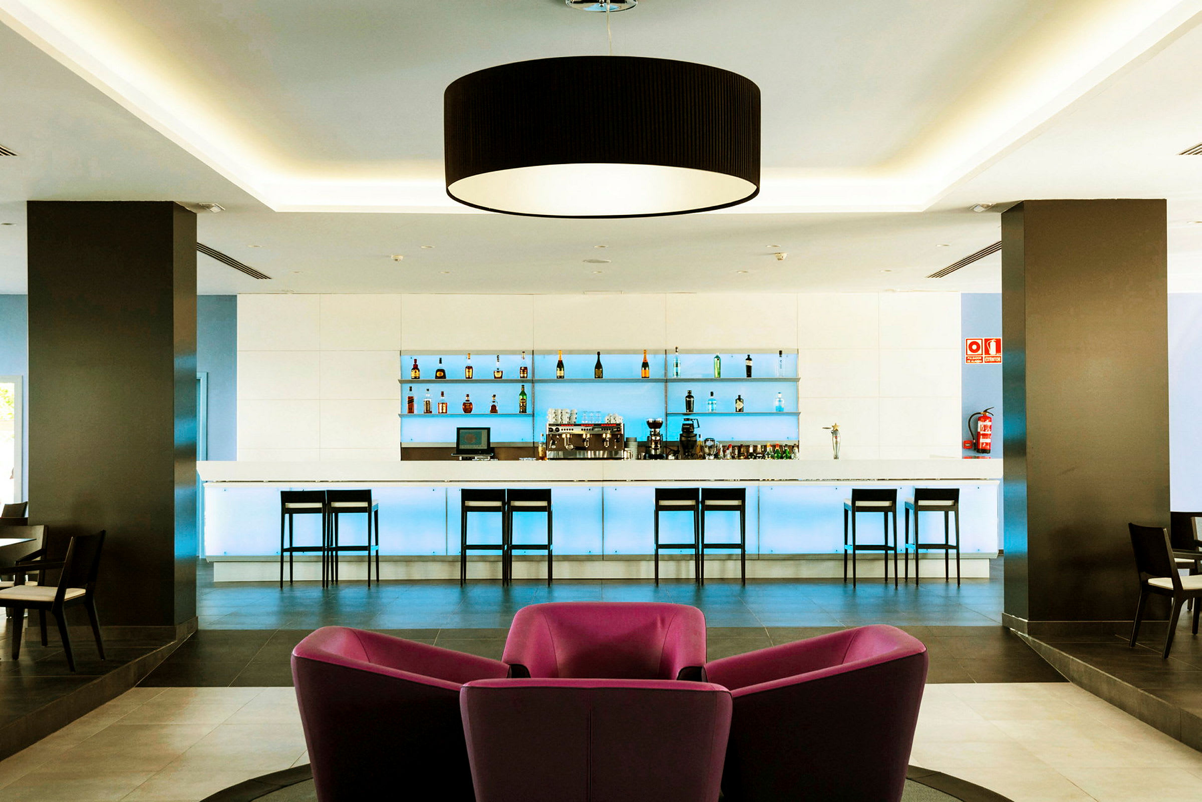 Moderne hotelbar med stole og flaskeudstilling. (AI-genereret tekst)