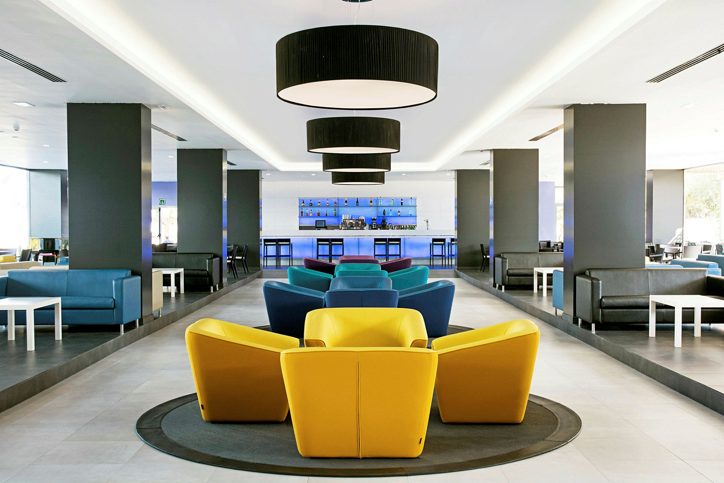 Moderne lounge med farverige stole og bar i baggrunden. (AI-genereret tekst)