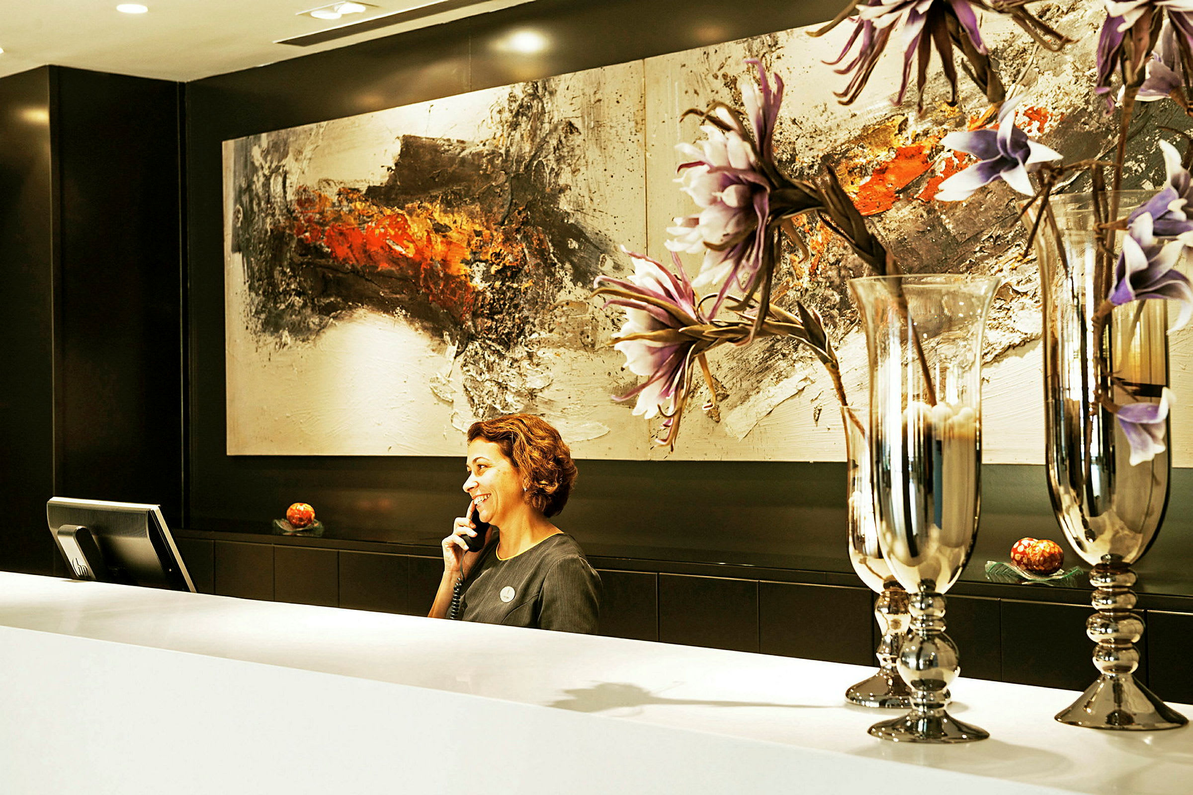 Reception med kunstværk og dekorative glasvaser med blomster. (AI-genereret tekst)