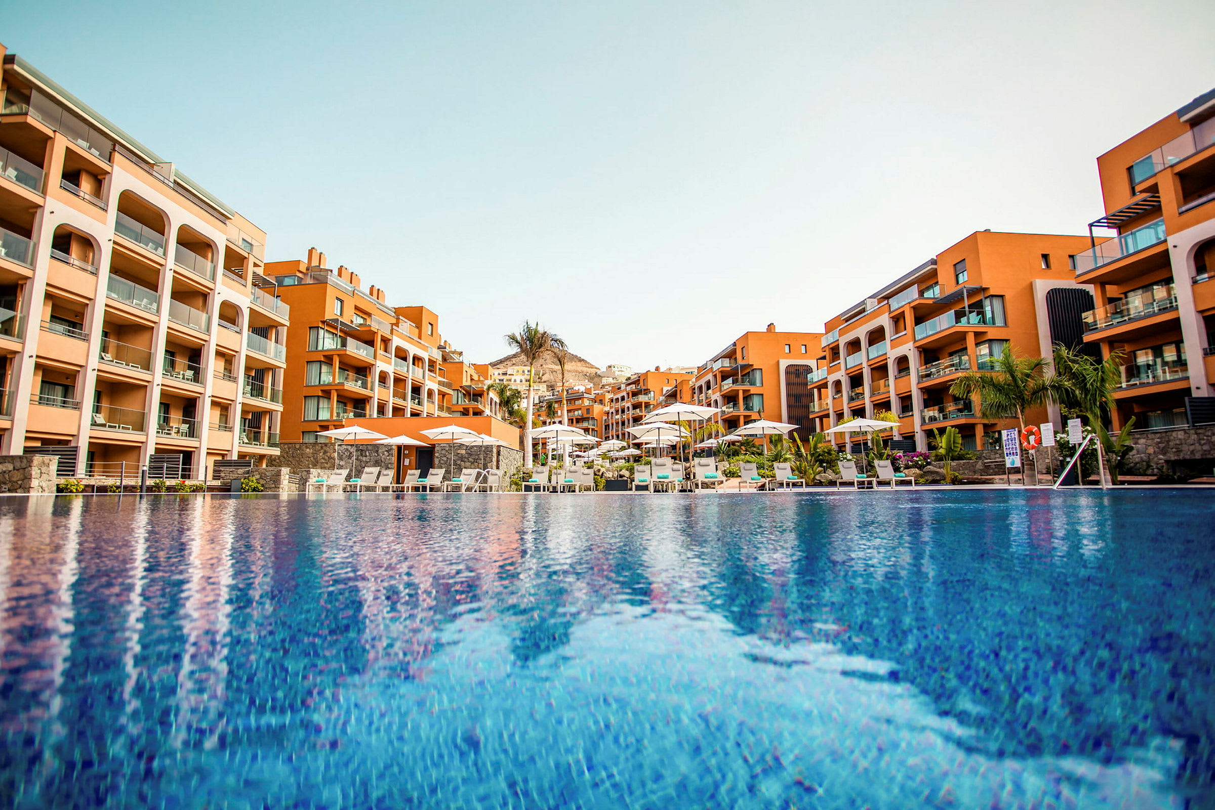 Moderne hotel med lejligheder i orange farve ved poolområde. (AI-genereret tekst)