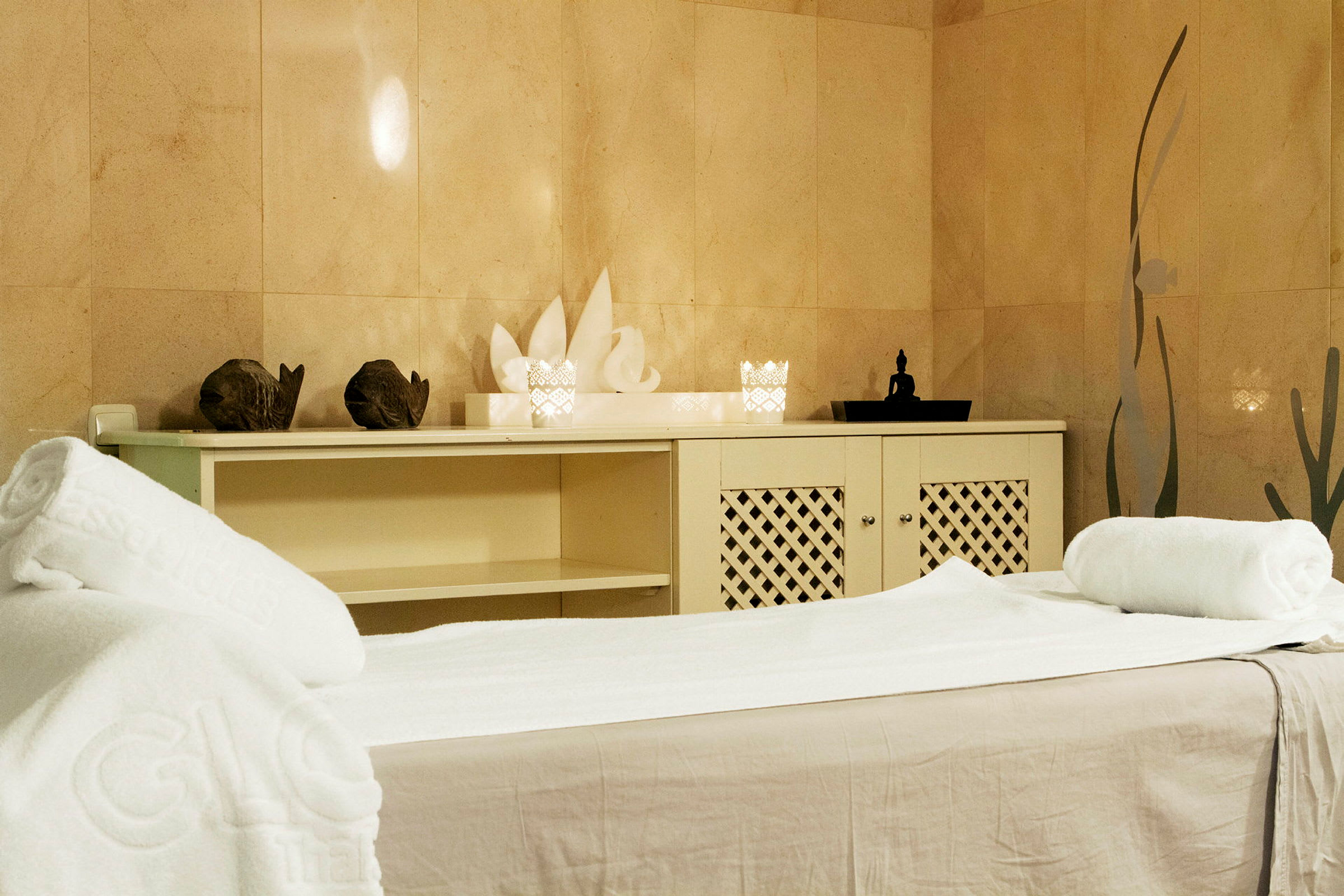 Et spa-rum med massageseng, håndklæder og dekorationer. (AI-genereret tekst)