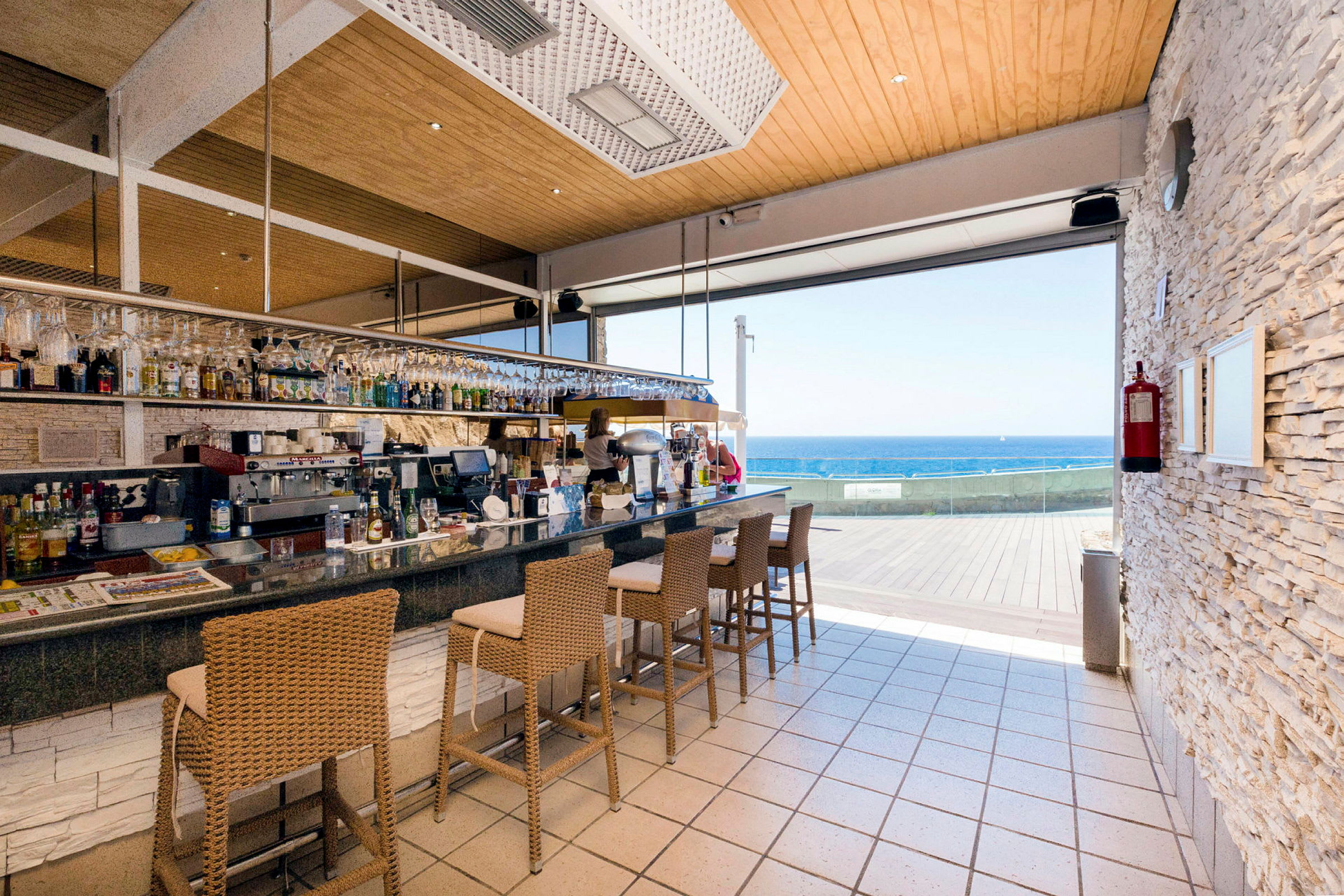En bar med høje stole og udsigt over havet. (AI-genereret tekst)