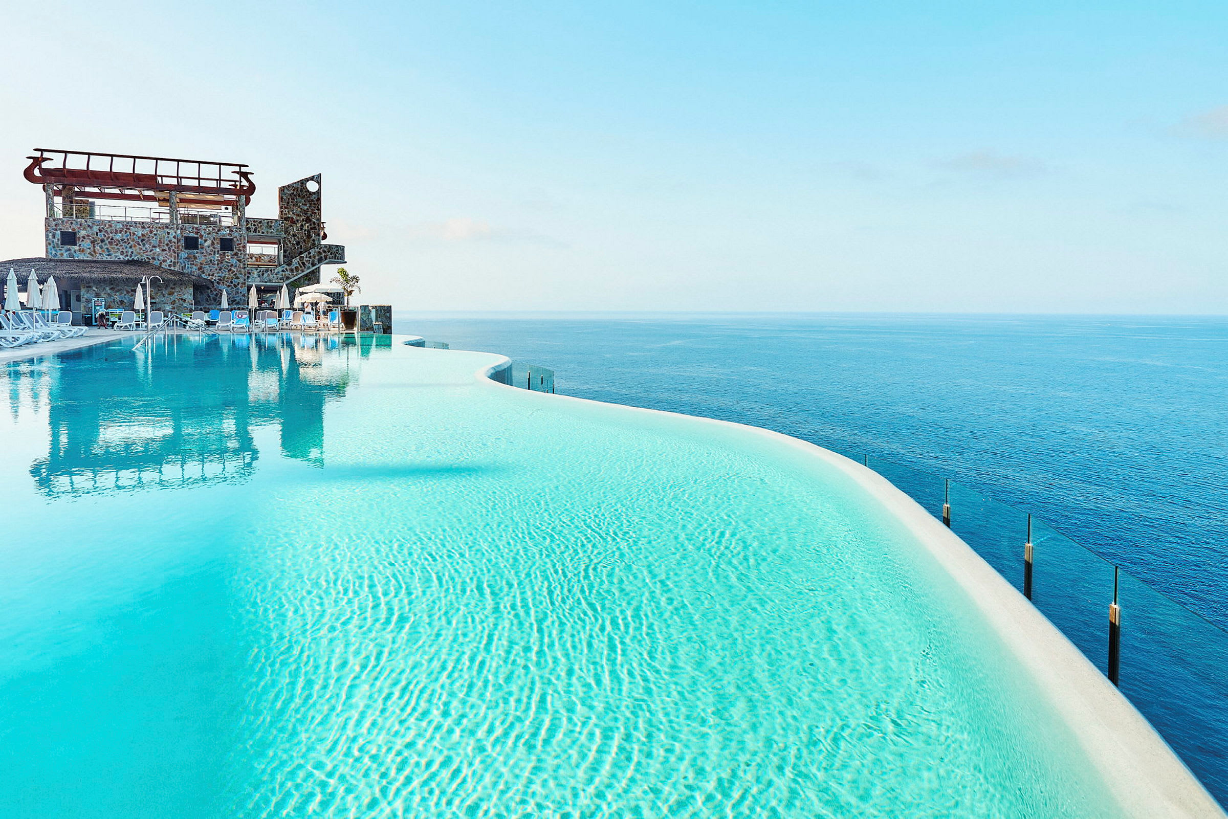 Infinitypool med klart blåt vand og udsigt over havet. (AI-genereret tekst)