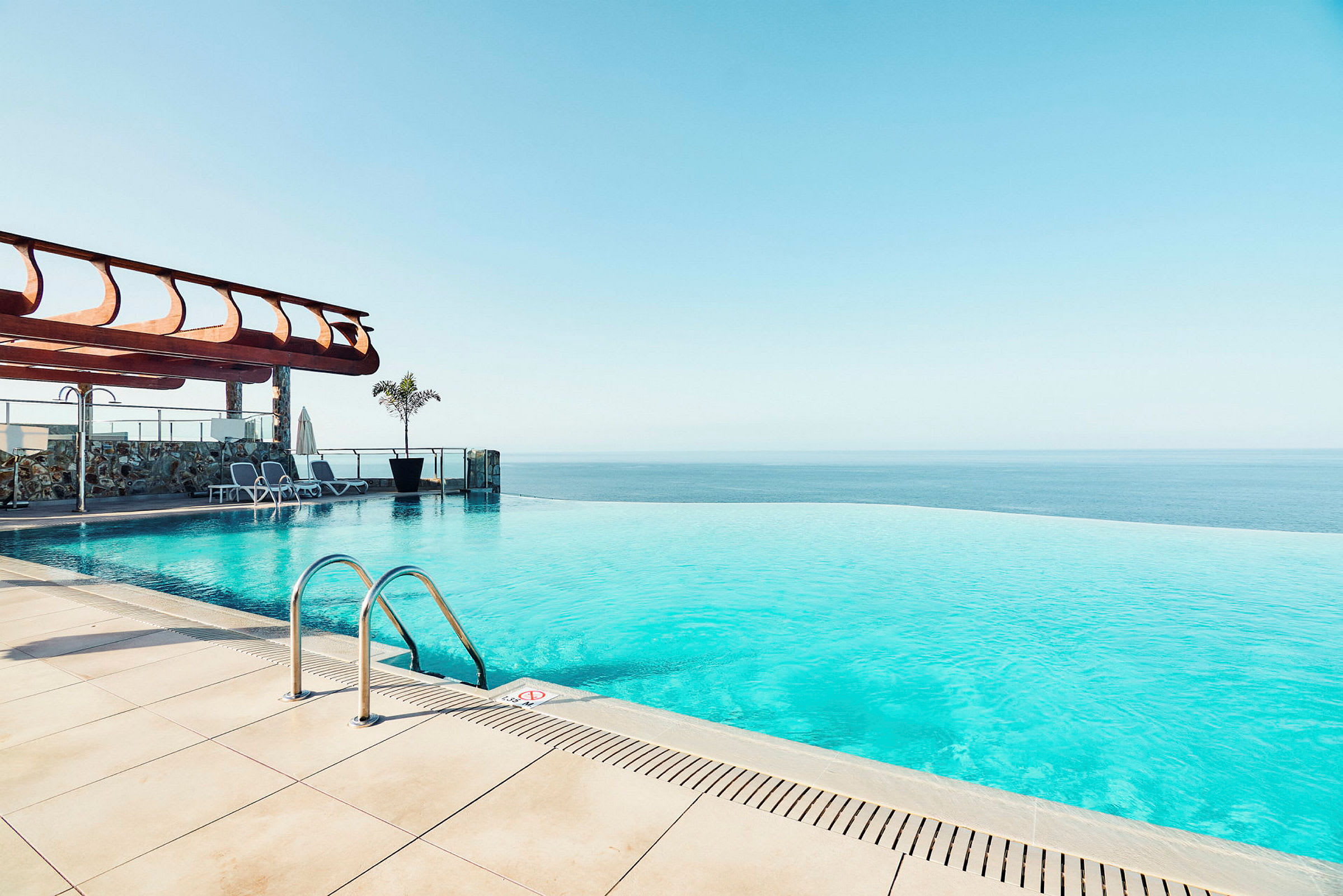 En infinity-pool med havudsigt og liggestole ved kanten. (AI-genereret tekst)