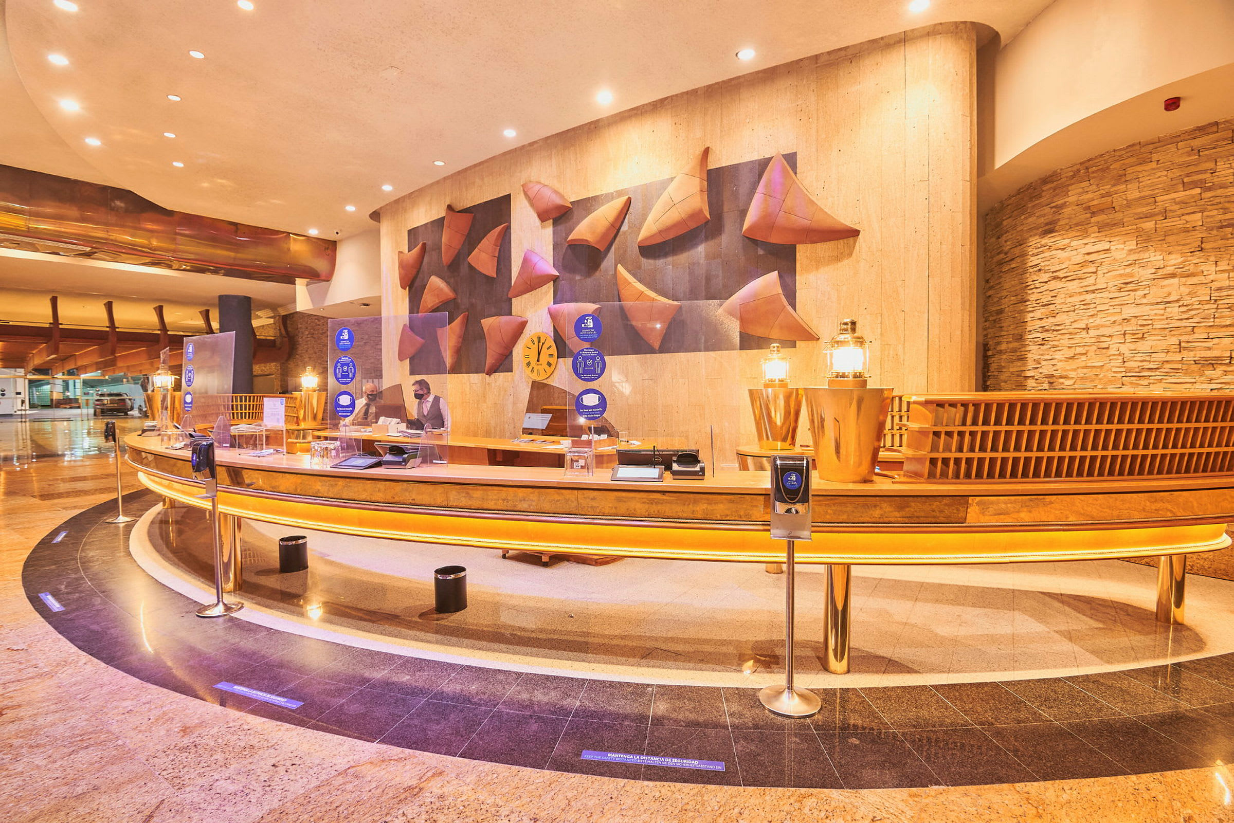 Hotellets reception med buet skranke, dekorative elementer og en medarbejder ved arbejdsstationen. (AI-genereret tekst)