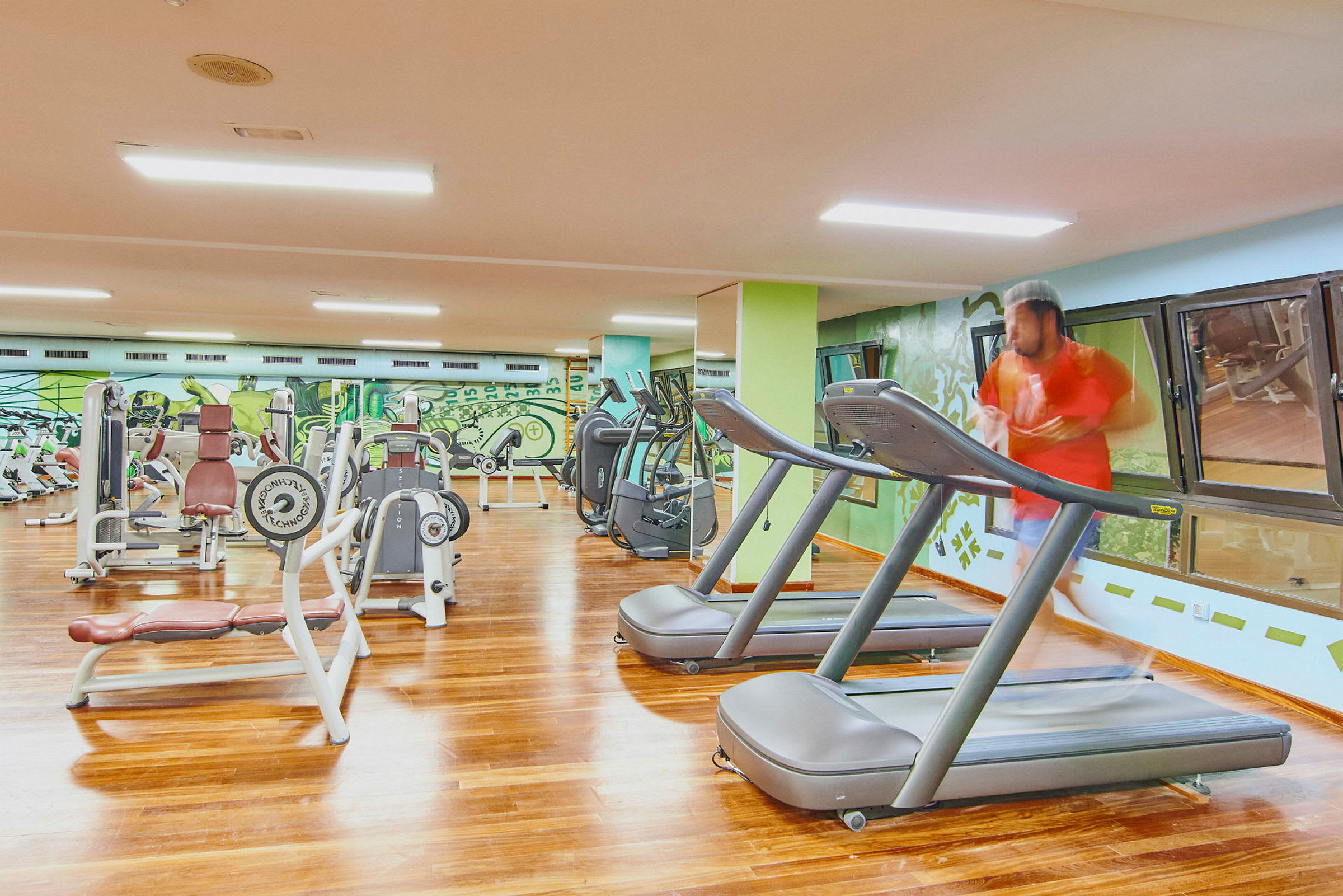 Et fitnesscenter med træningsmaskiner og løbebånd. (AI-genereret tekst)