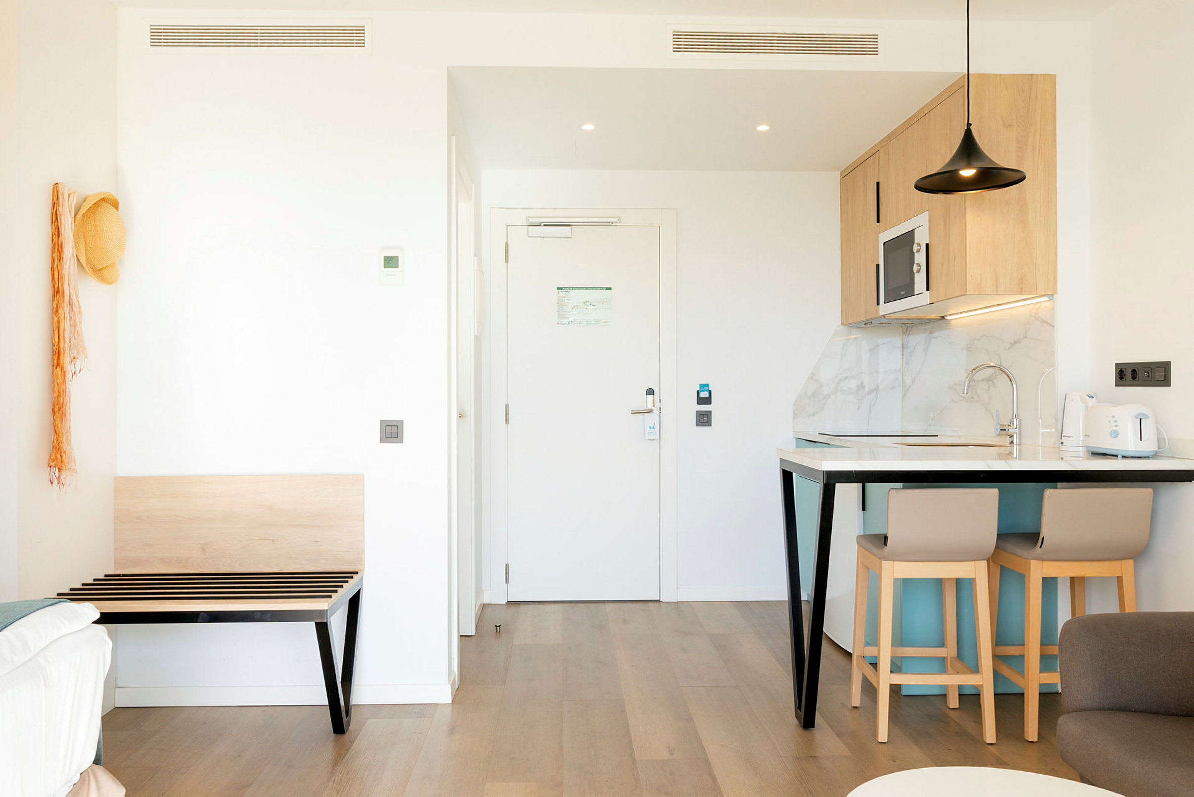 Billede af et moderne hotelværelse med køkkenområde og indgang. (AI-genereret tekst)