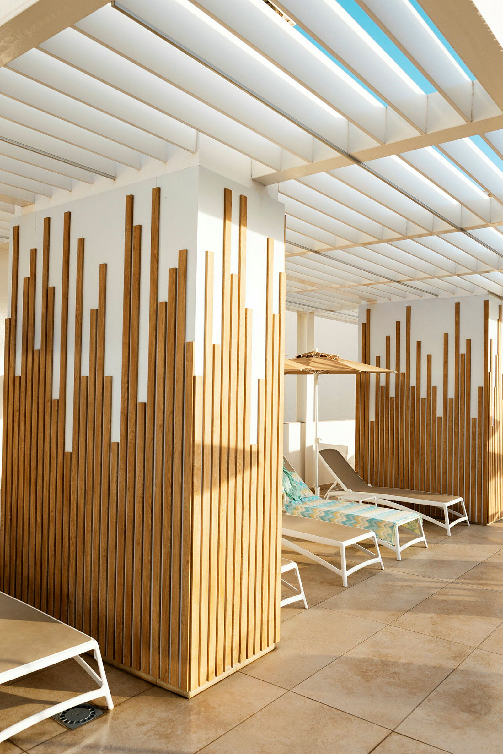 Udendørsområde med solsenge under en pergola og træpaneler. (AI-genereret tekst)
