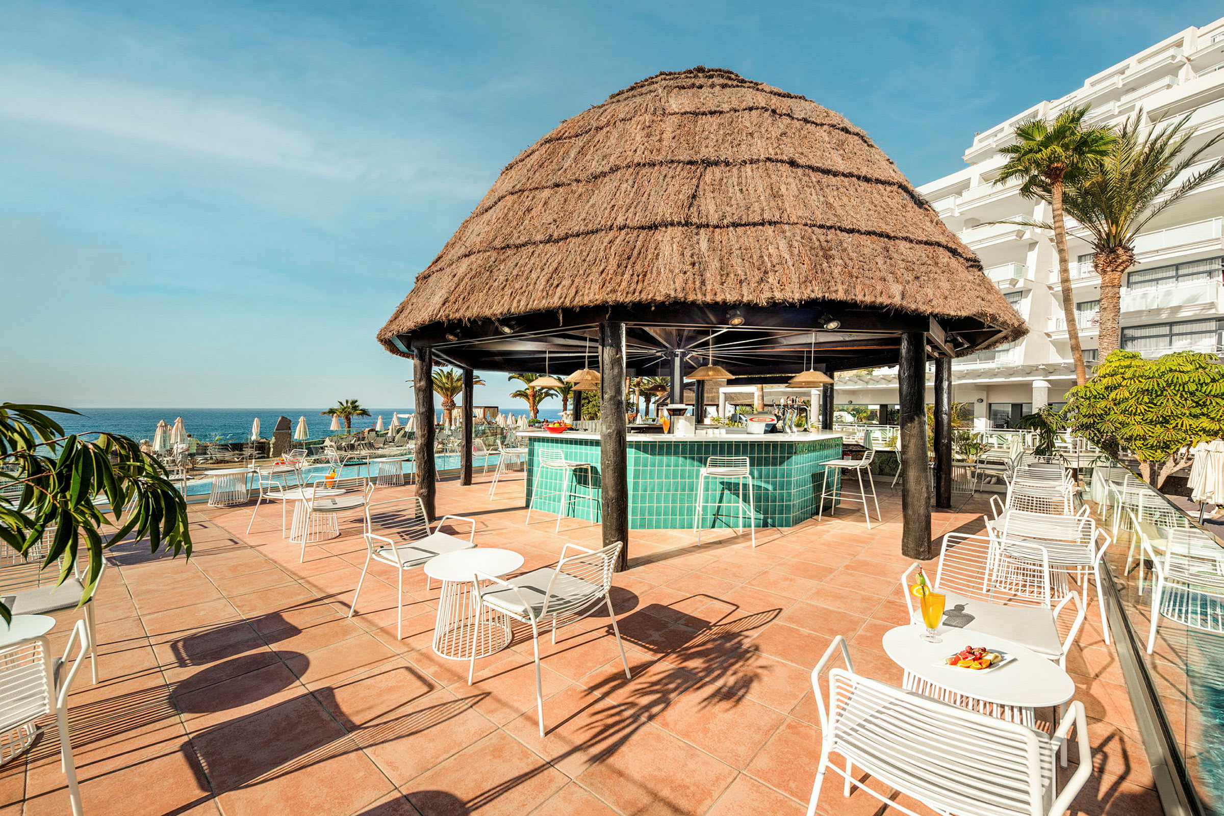 Strandbar med stråtag og siddepladser udendørs. (AI-genereret tekst)