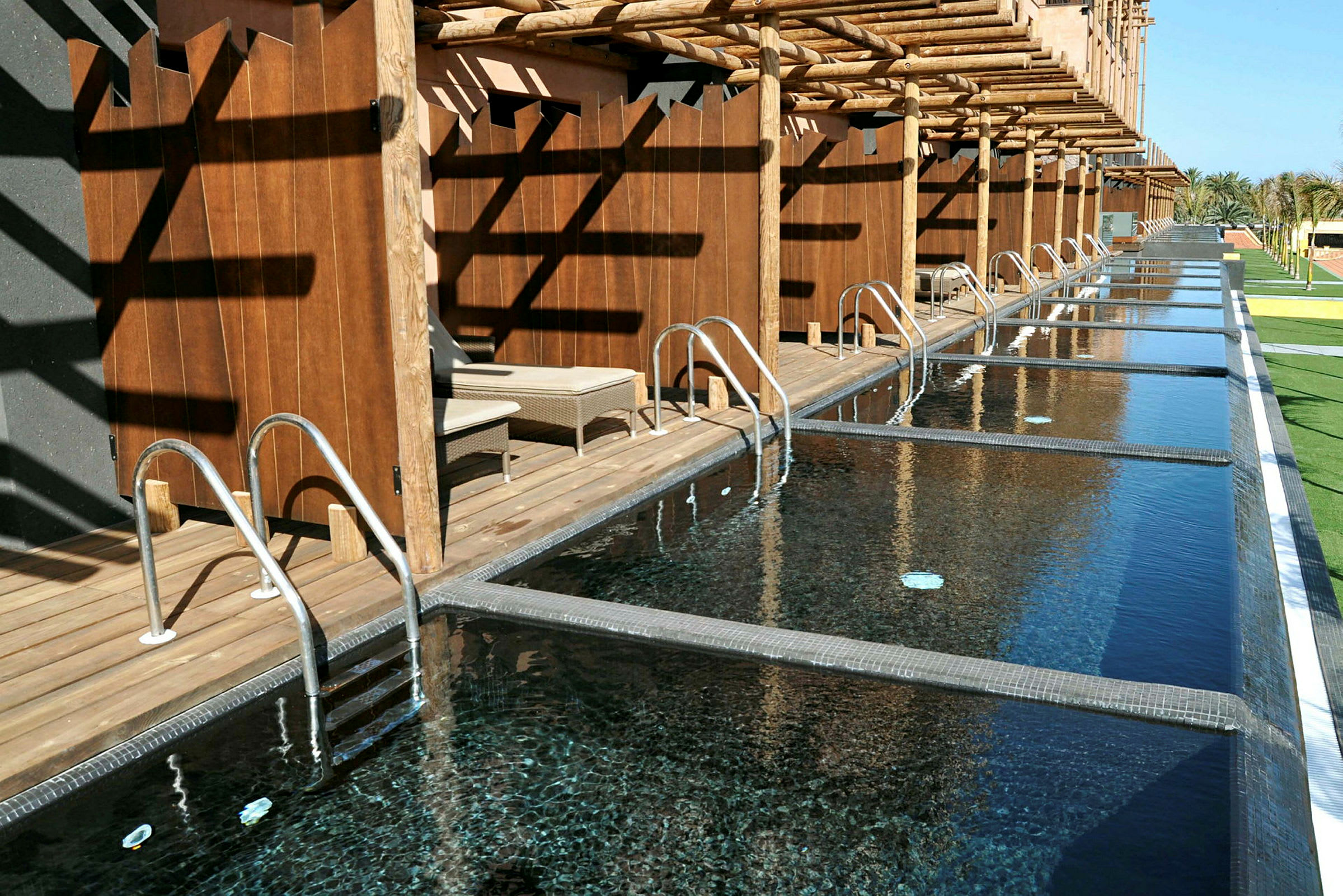 Private pools med træterrasser og ryglæn samt solsenge. (AI-genereret tekst)