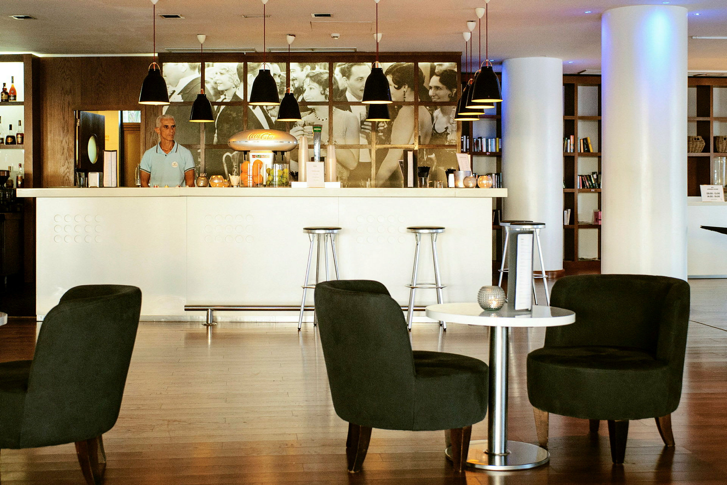 Moderne bar med hvide og mørke møbler samt en reol med bøger i baggrunden. (AI-genereret tekst)