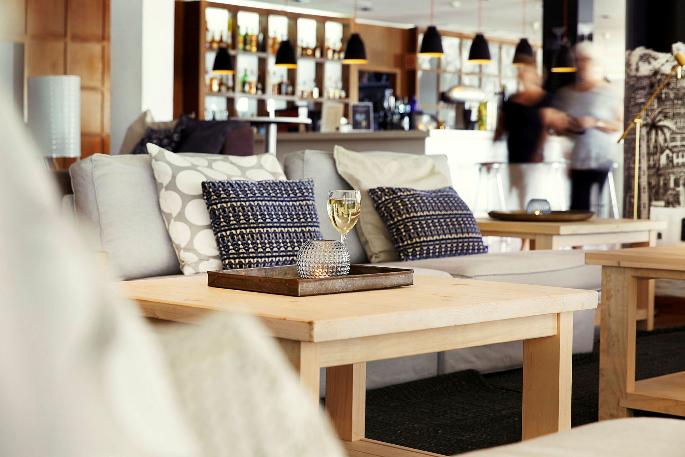 Et sofabord med et glas med drik foran en sofa i en lounge. (AI-genereret tekst)