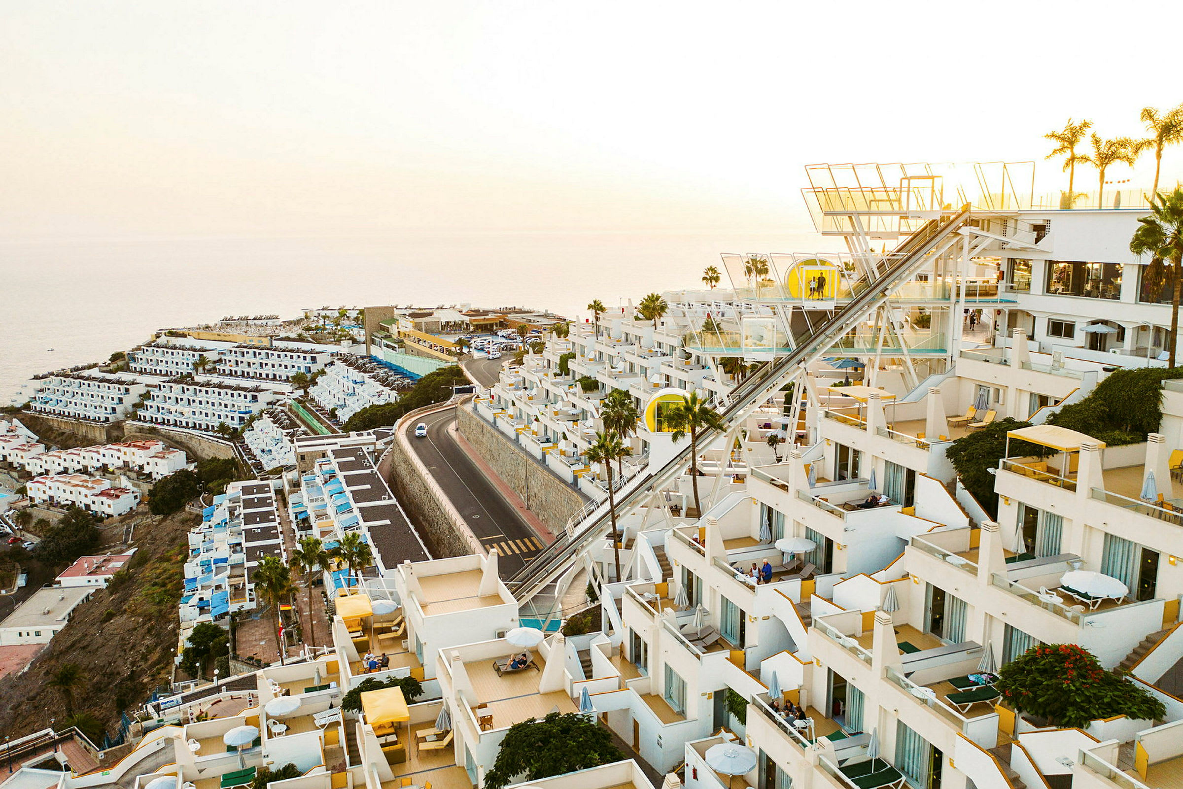 Hotel med hvide terrassebygninger og havudsigt. (AI-genereret tekst)