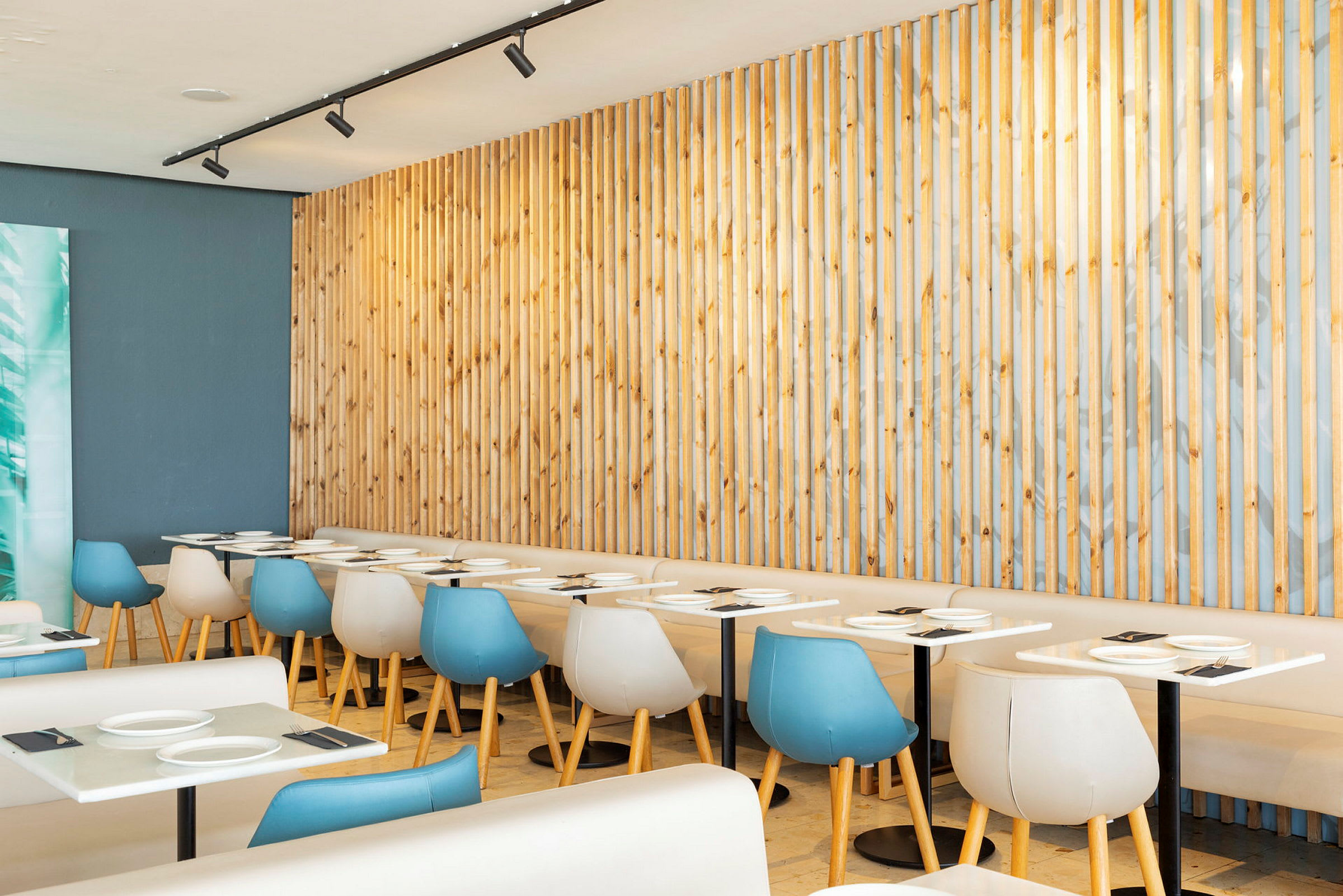 Restaurant med lyse borde og moderne stole foran en træpanel. (AI-genereret tekst)